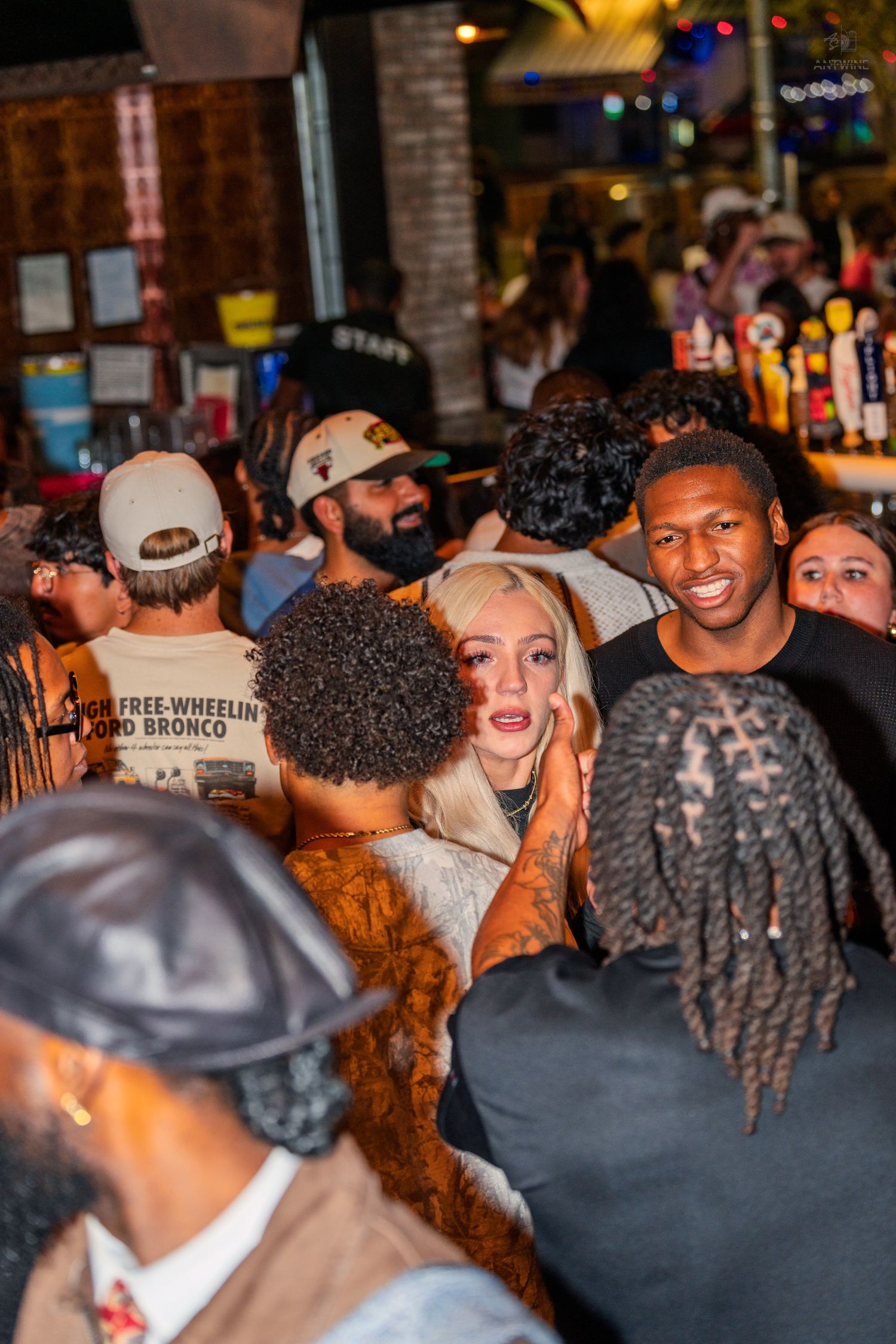 Diverse crowd of people socializing at a busy outdoor bar at night.