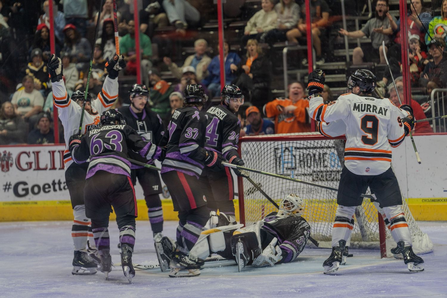 Players celebrate a goal in front of the net during an ice hockey game.
