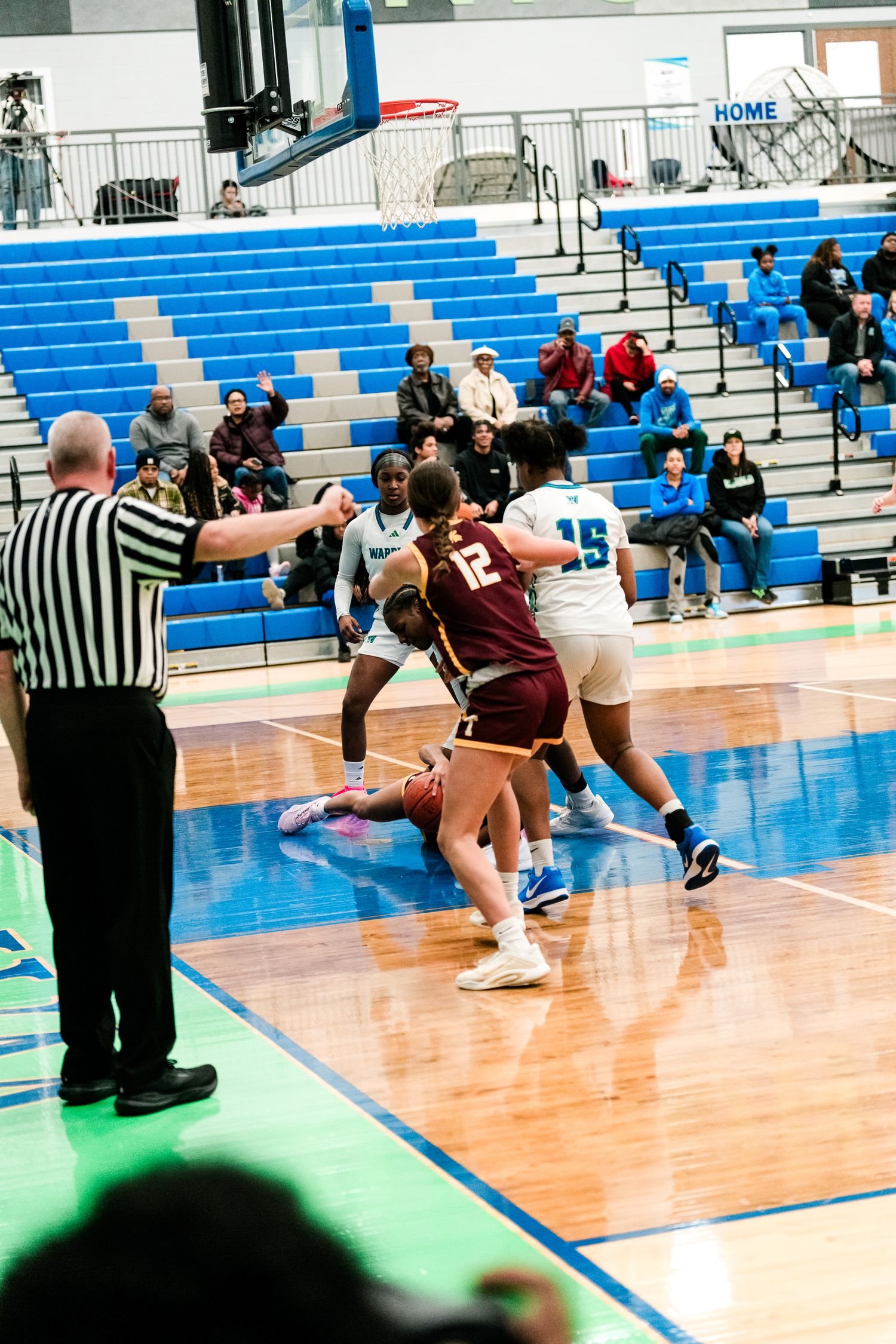Referee signals as Warriors #15 defends Turpin #12 in a girls high school basketball game.