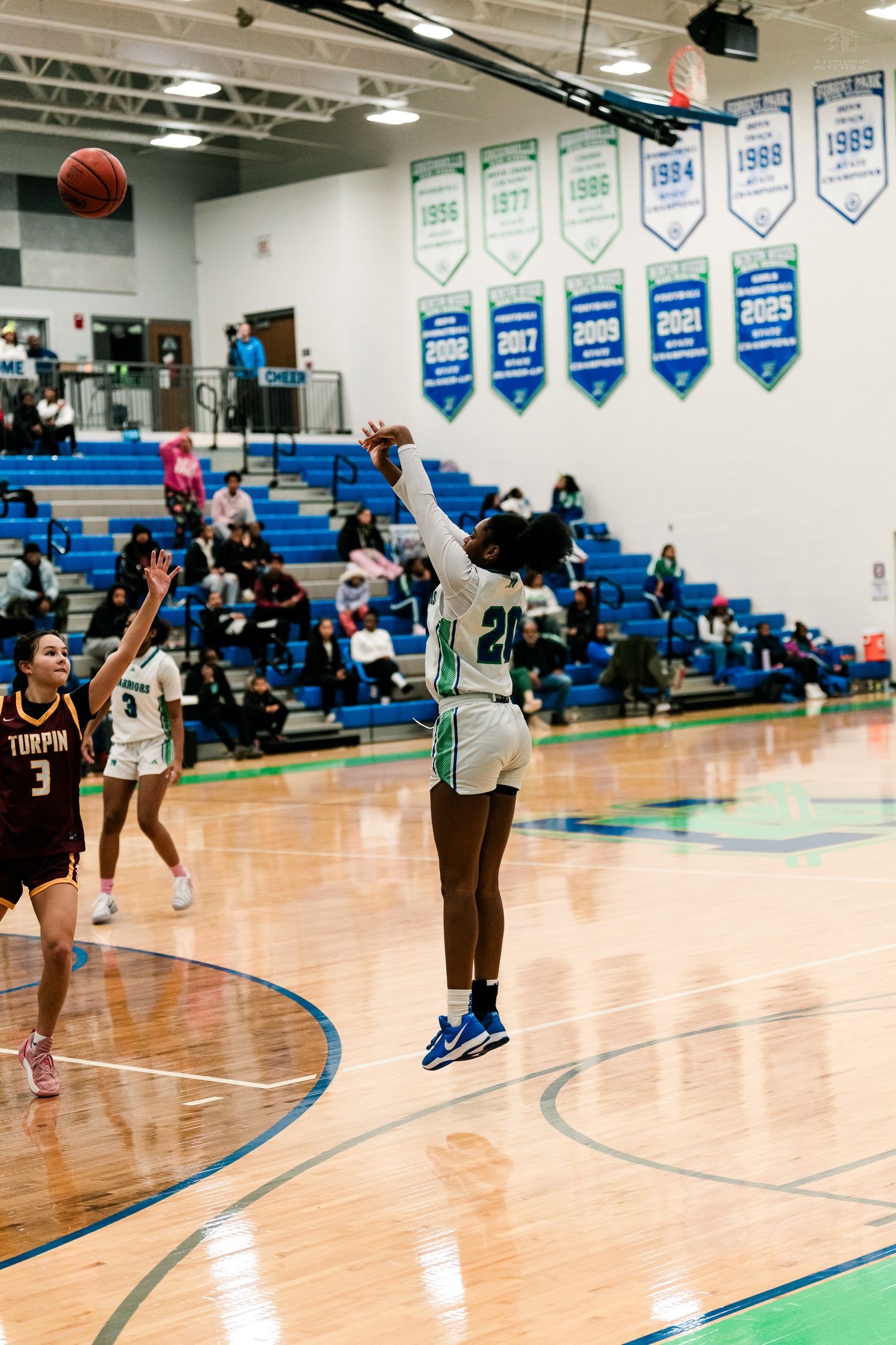 A Warriors player shoots a jump shot while Turpin defenders watch during a girls high school basketball game.
