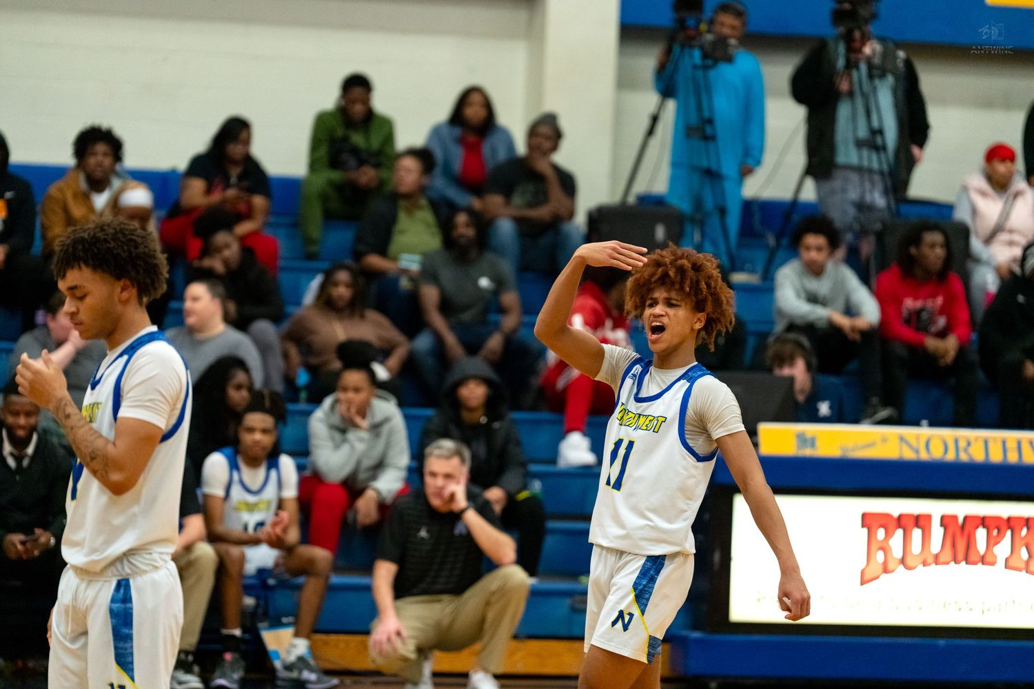Northwest Knights player number 11 reacts emotionally during a high school basketball game with teammate number 1 nearby.