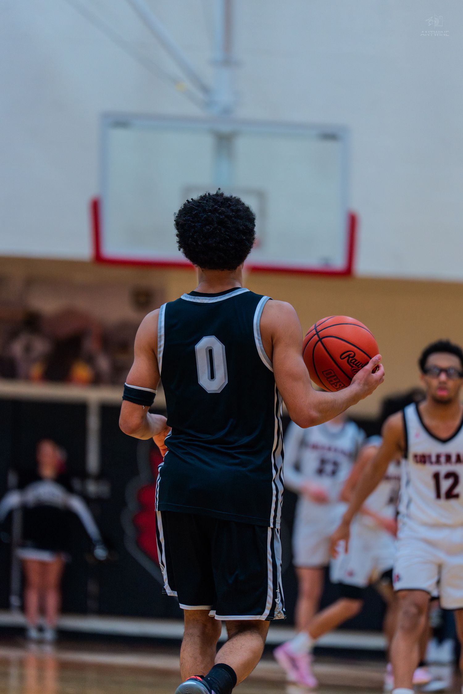 High school basketball player wearing jersey #0 dribbles ball downcourt during a competitive game.