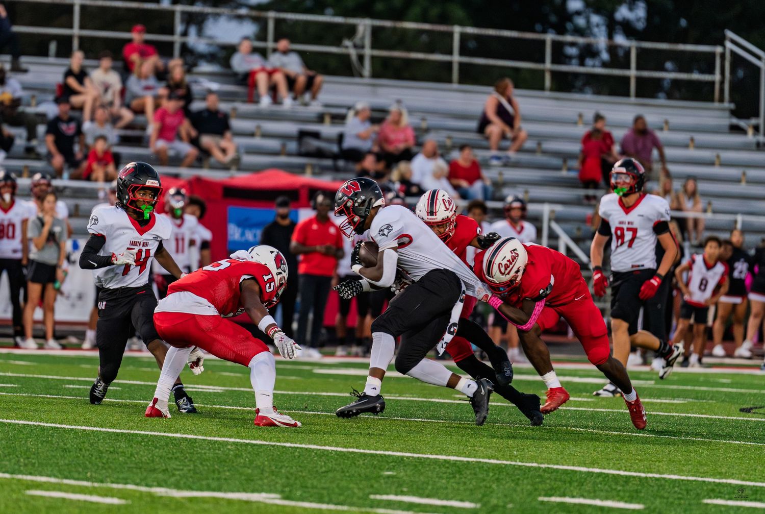 Colerain defenders in red uniforms prepare to tackle a ball carrier during a high school football game.