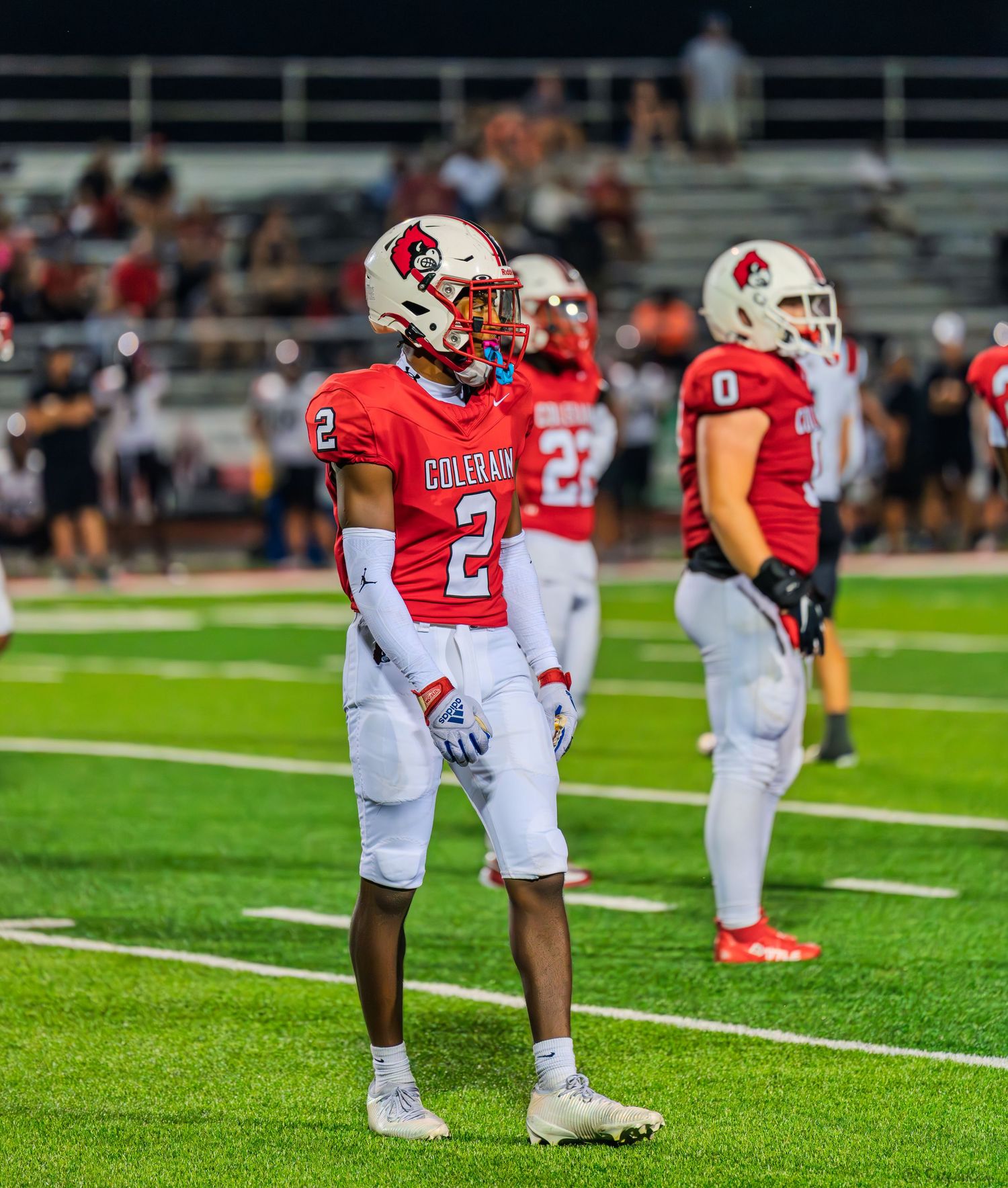 Colerain Cardinals player #2 stands on the field with teammates during a night football game.