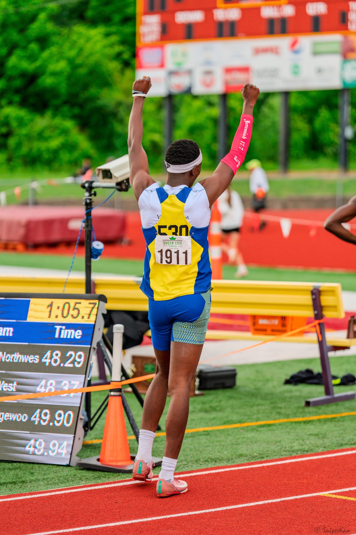 Track athlete number 1911 raises arms in victory after winning race at championship meet.