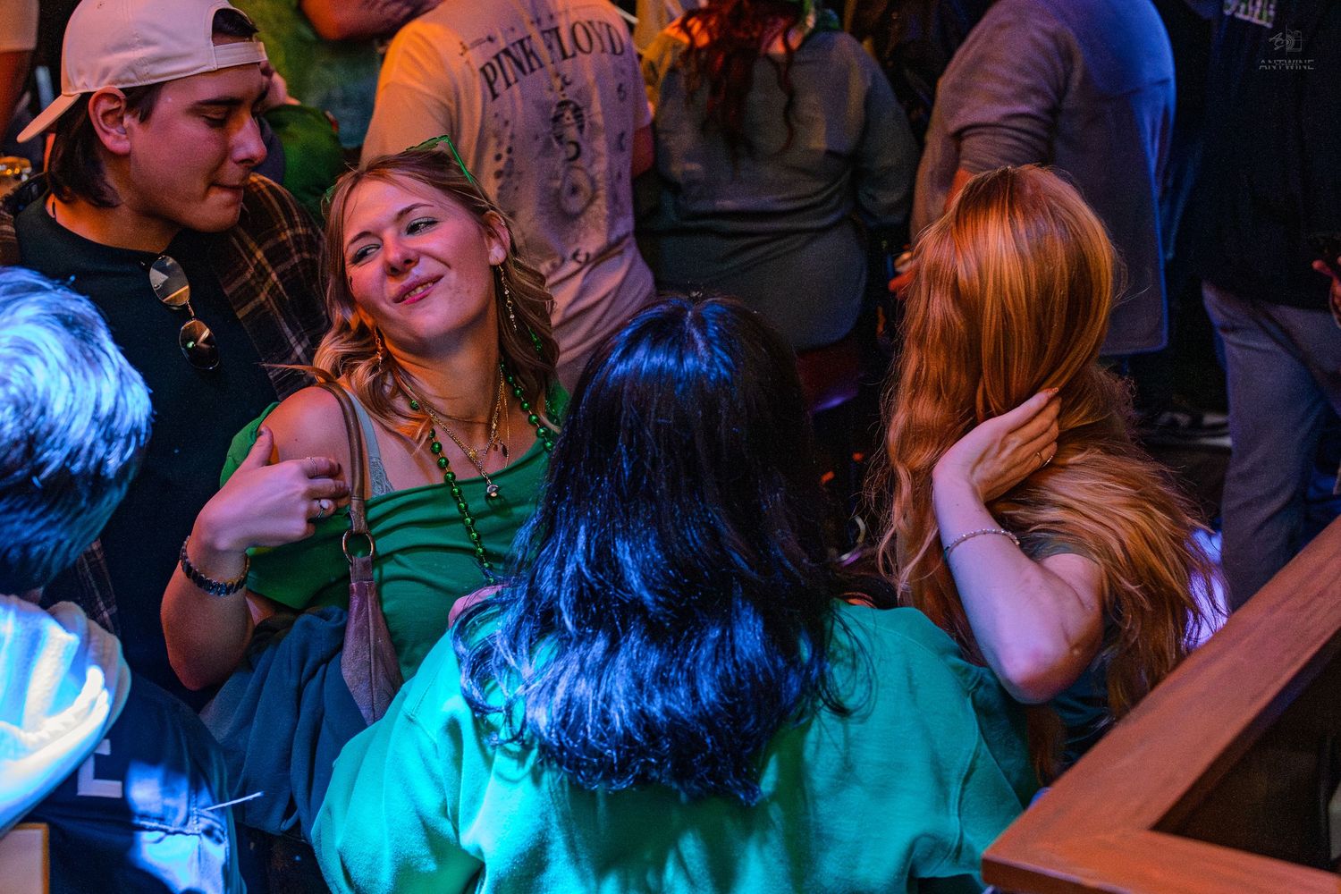 Group of friends laughing and socializing at a festive St. Patrick's Day bar party.