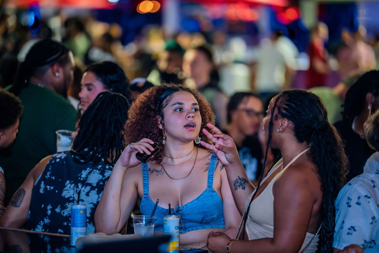 A group of women socialize and enjoy themselves at a lively outdoor nighttime event.