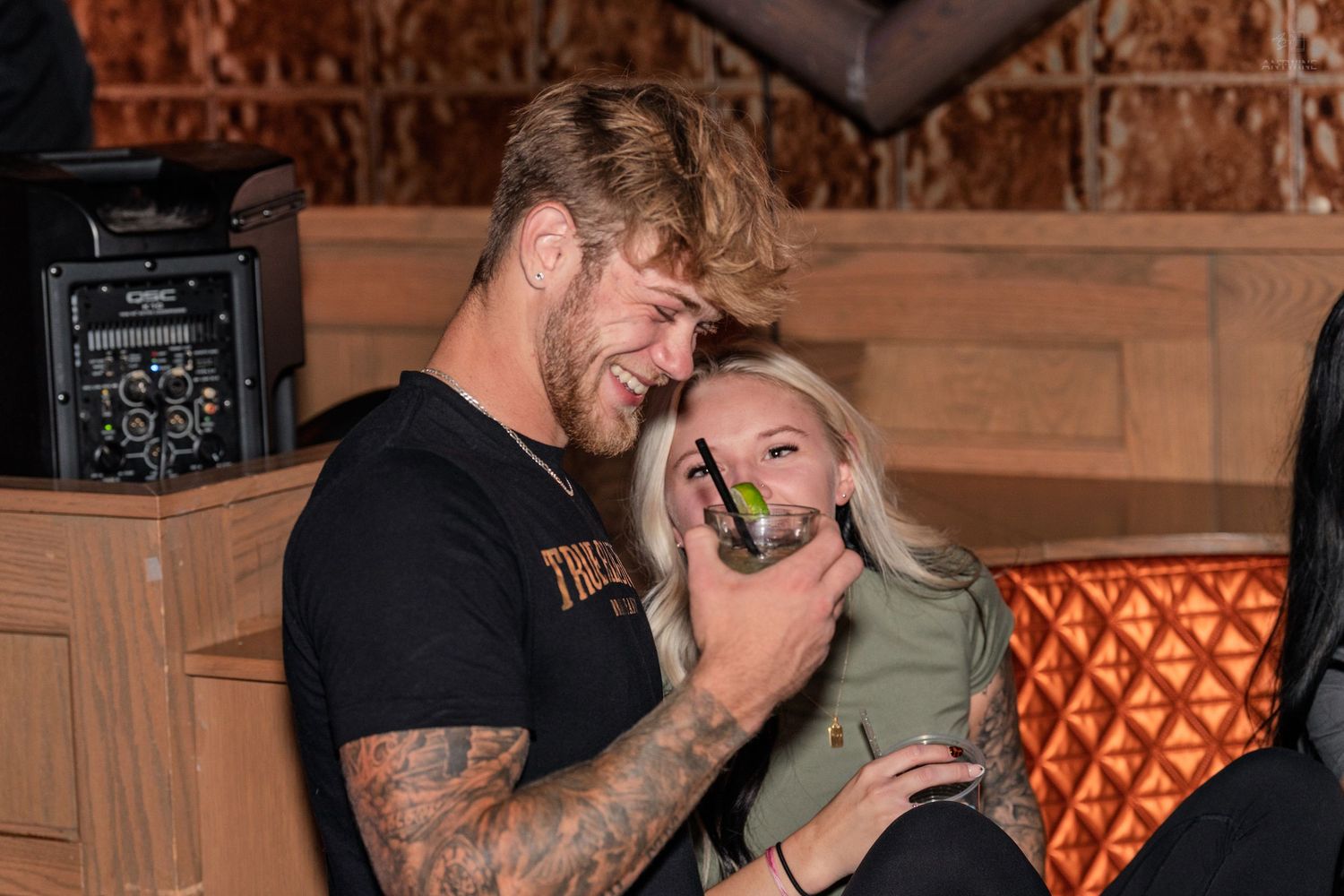 Tattooed couple sharing a close moment and laughing together at a bar.