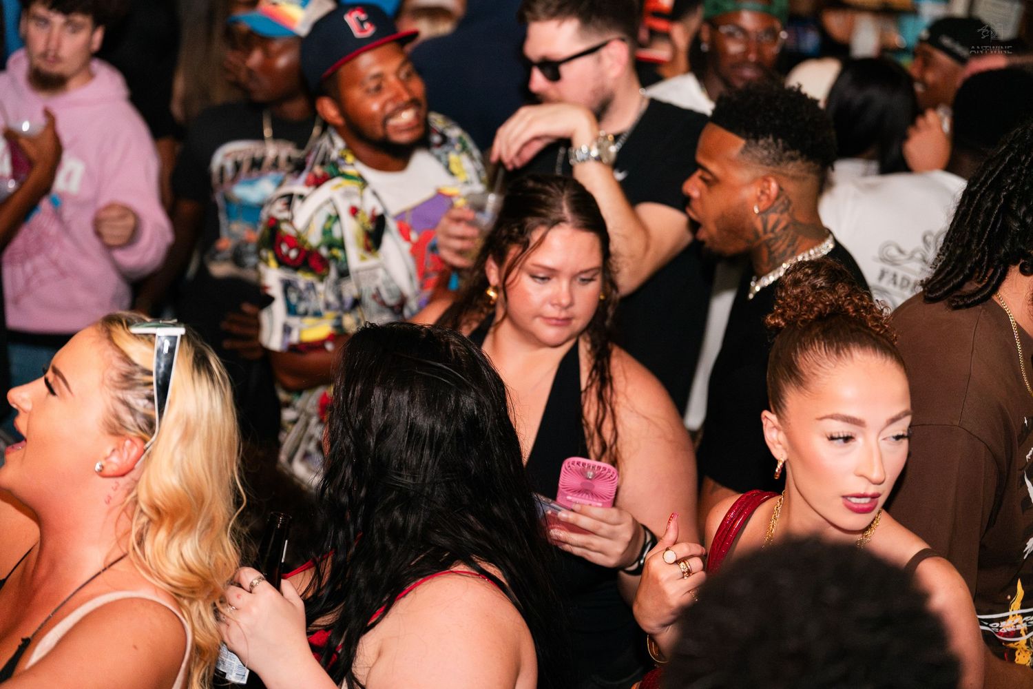 Diverse group of partygoers mingling at a crowded nightclub event.