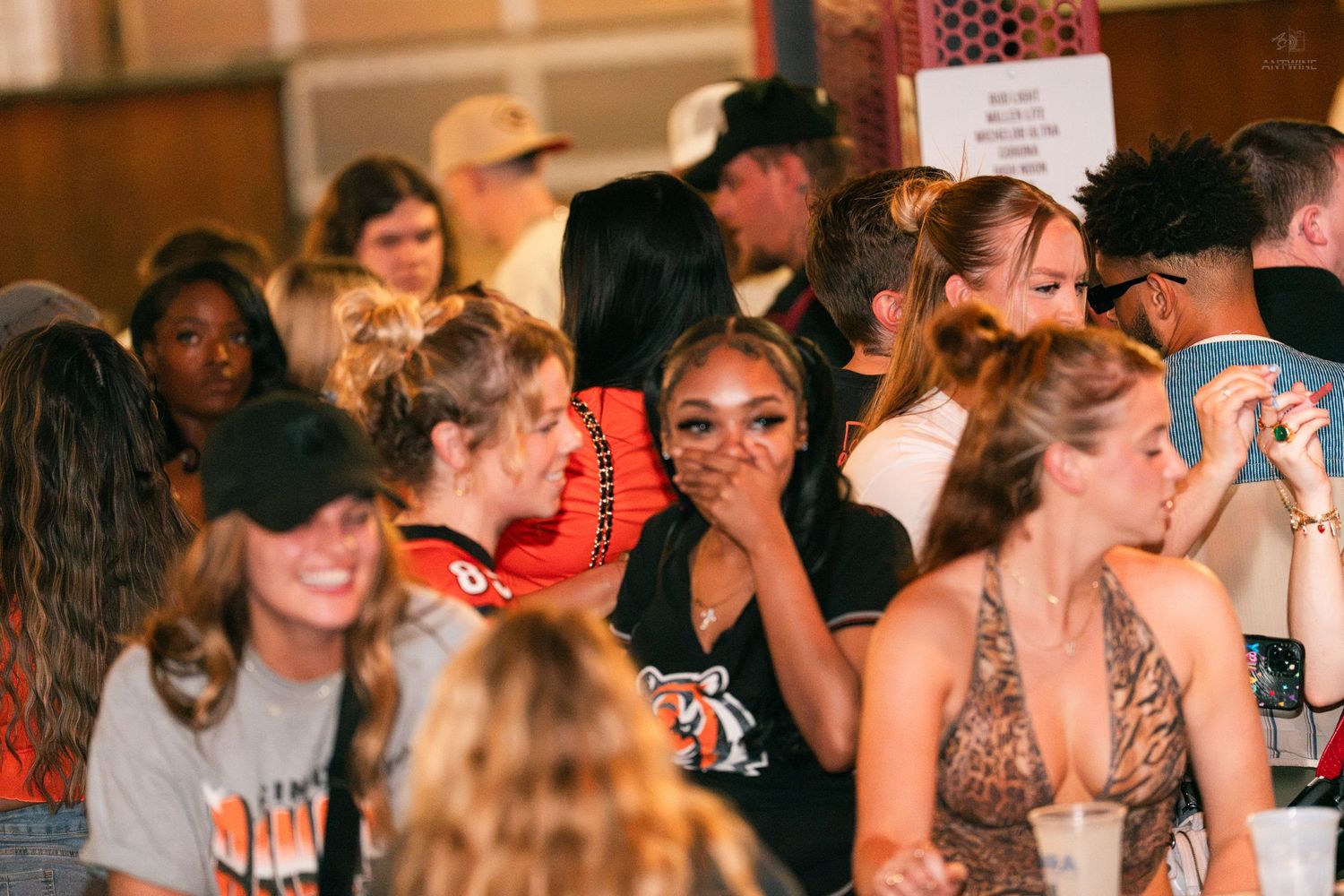 Diverse group of women laughing and socializing at a lively indoor party event.