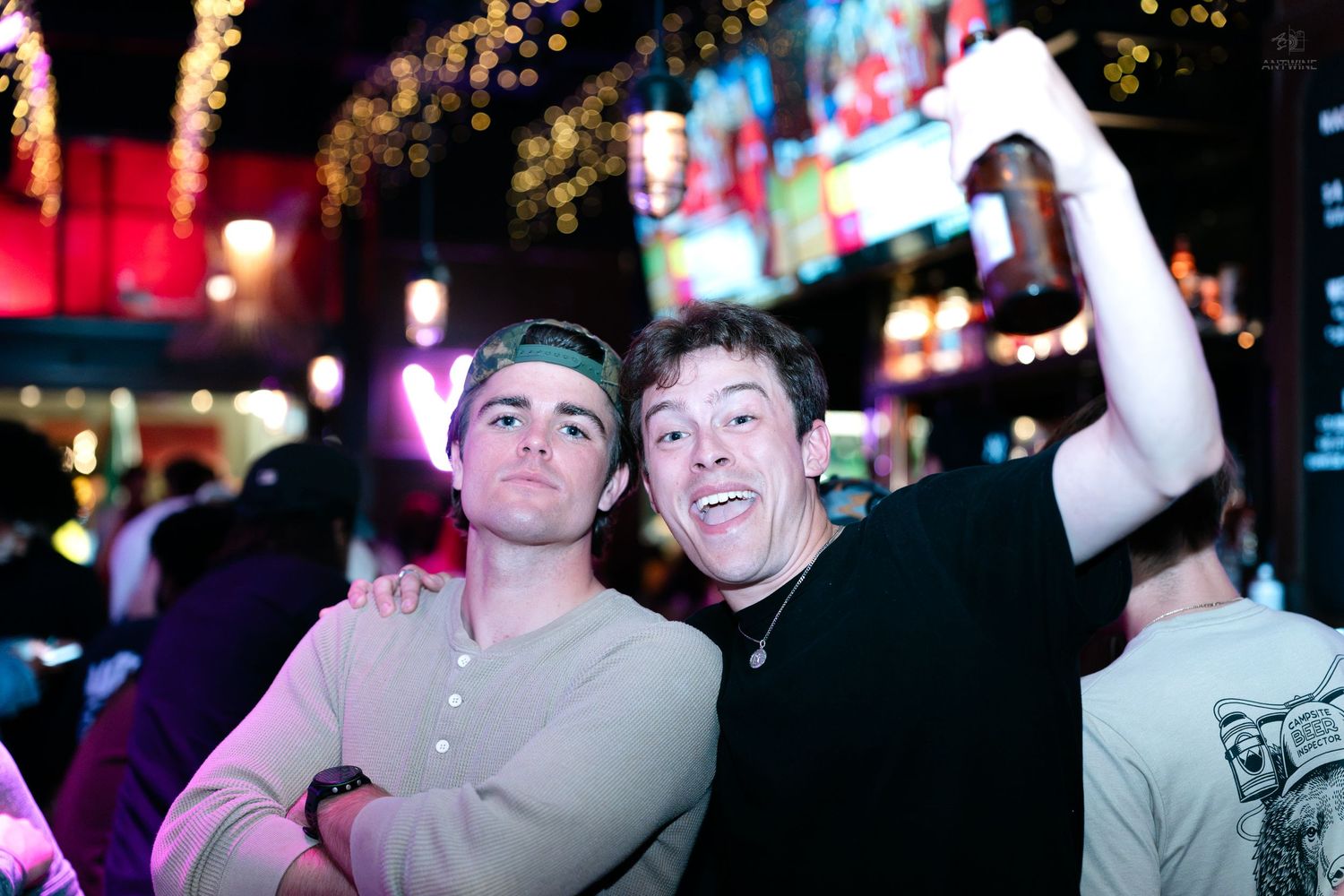 Two smiling young men celebrating together at a lively nightclub party.