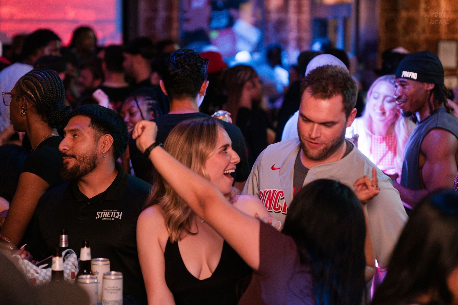 Man and woman dancing and socializing at a crowded indoor nightclub party.