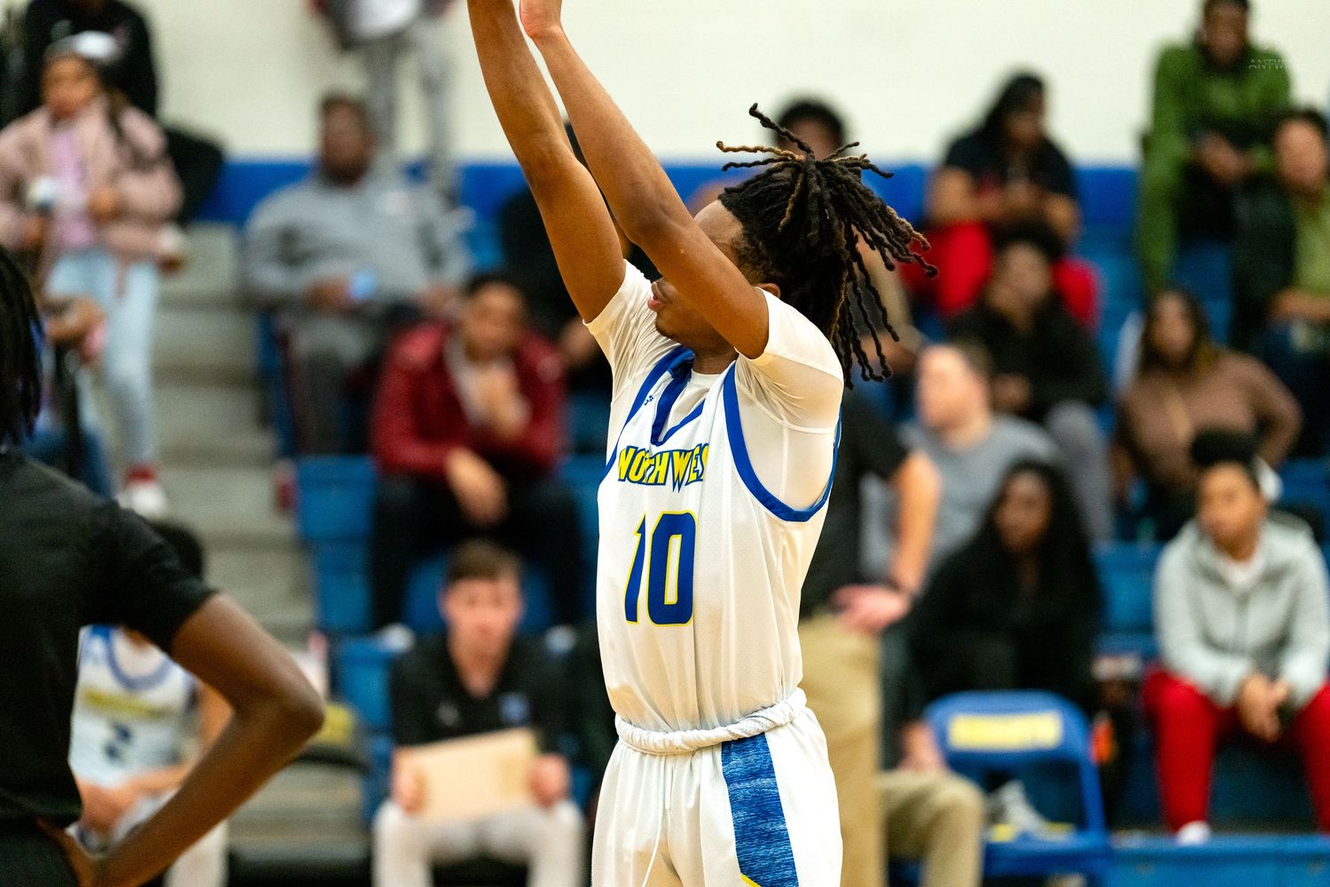 Northwest Knights player number 10 shoots a jump shot during a high school basketball game in a packed gymnasium.