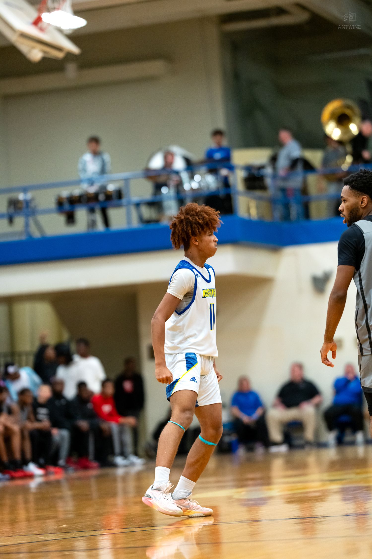 High school basketball player #11 in blue and white Northmen uniform stands on court during game.