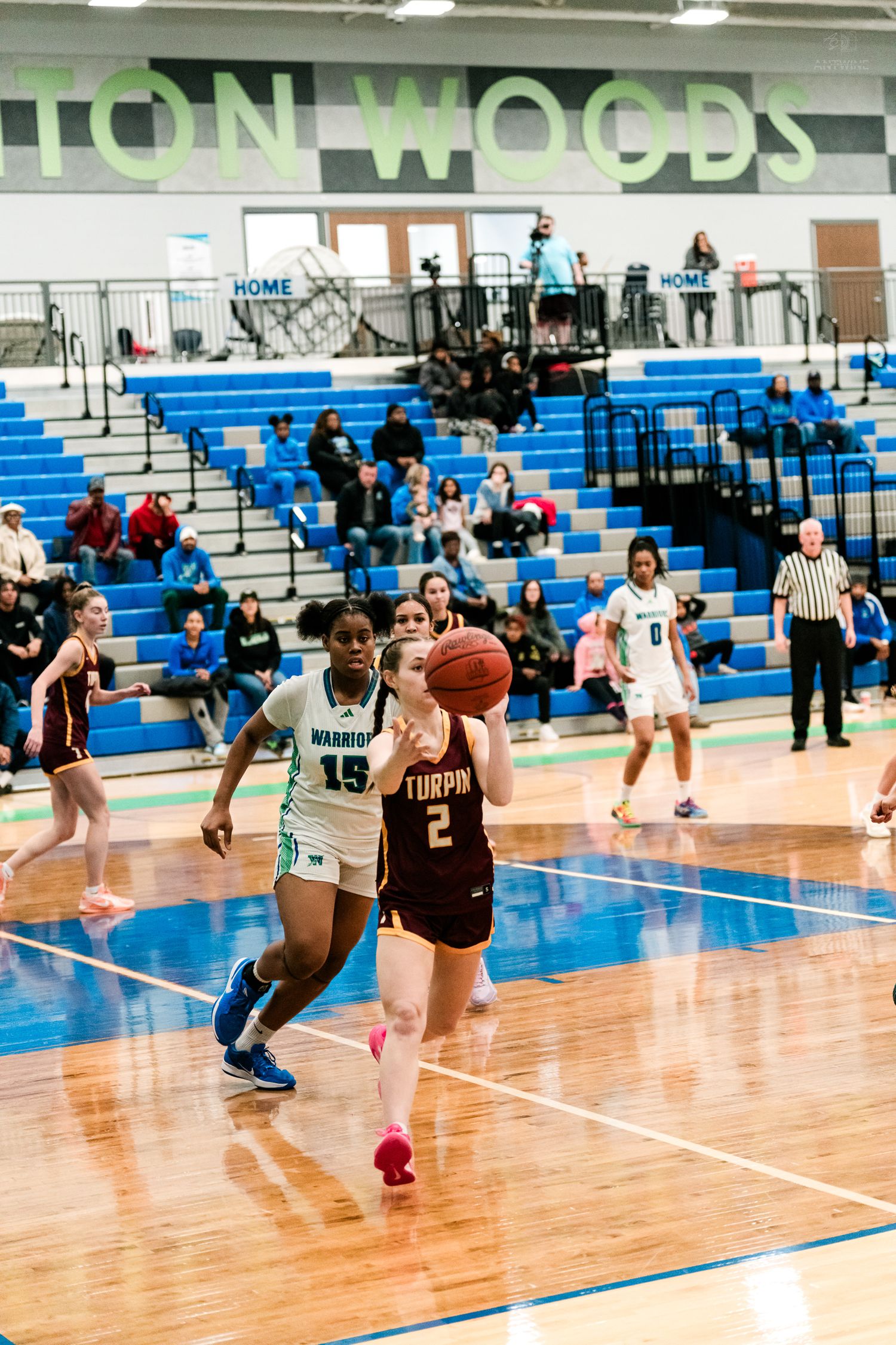 Turpin player #2 drives to the basket against Warriors defender #15 in a high school girls basketball game.