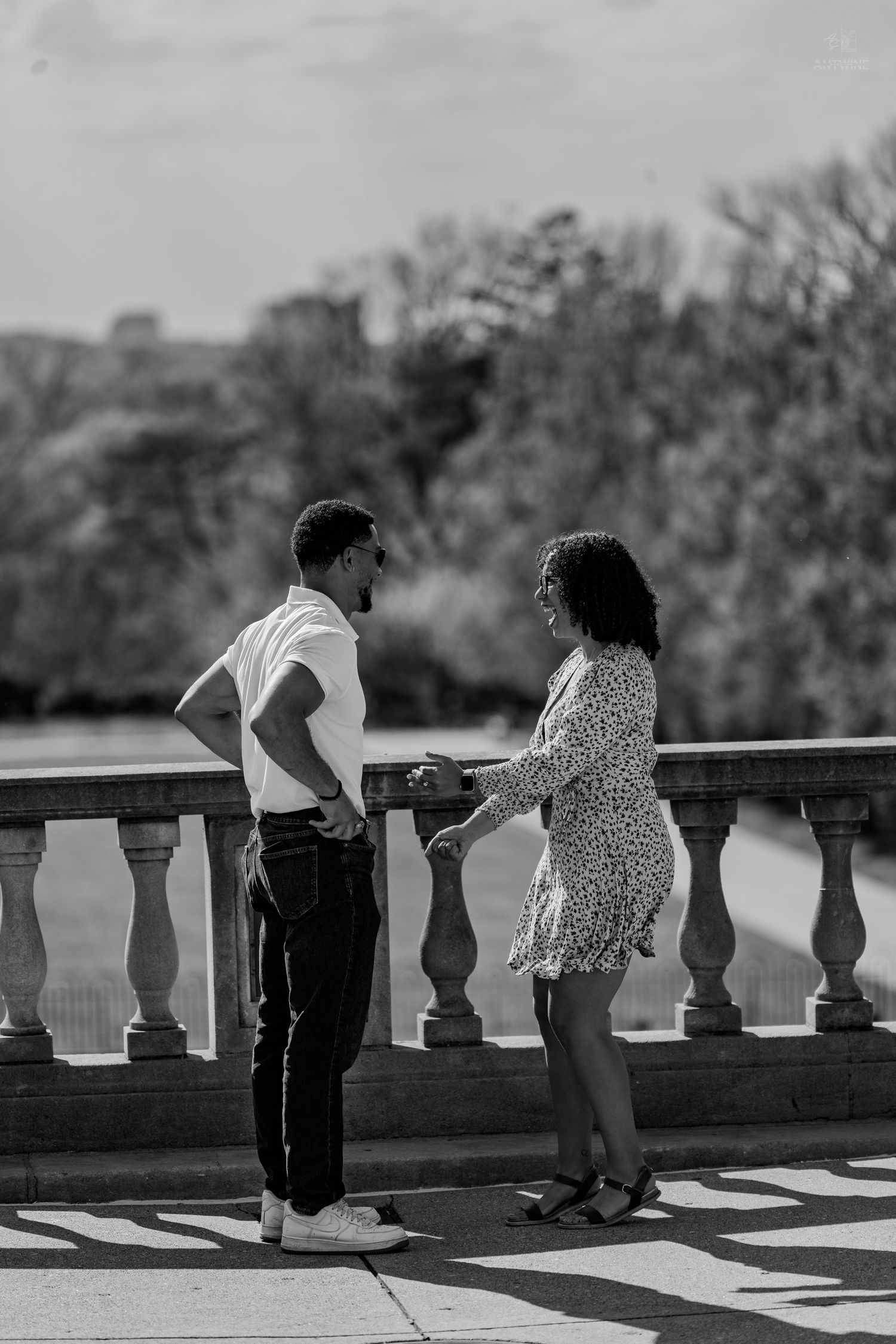 Black and white image of a couple sharing an intimate conversation on a scenic stone balcony.