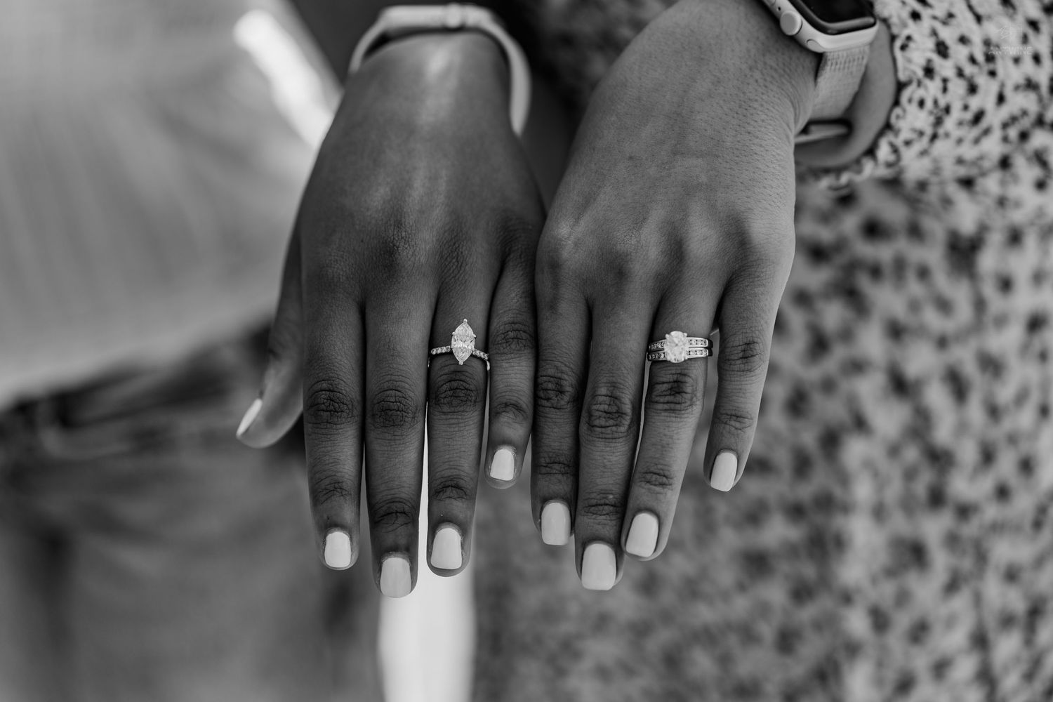 Black and white close-up of two women showing off their diamond engagement rings side by side.