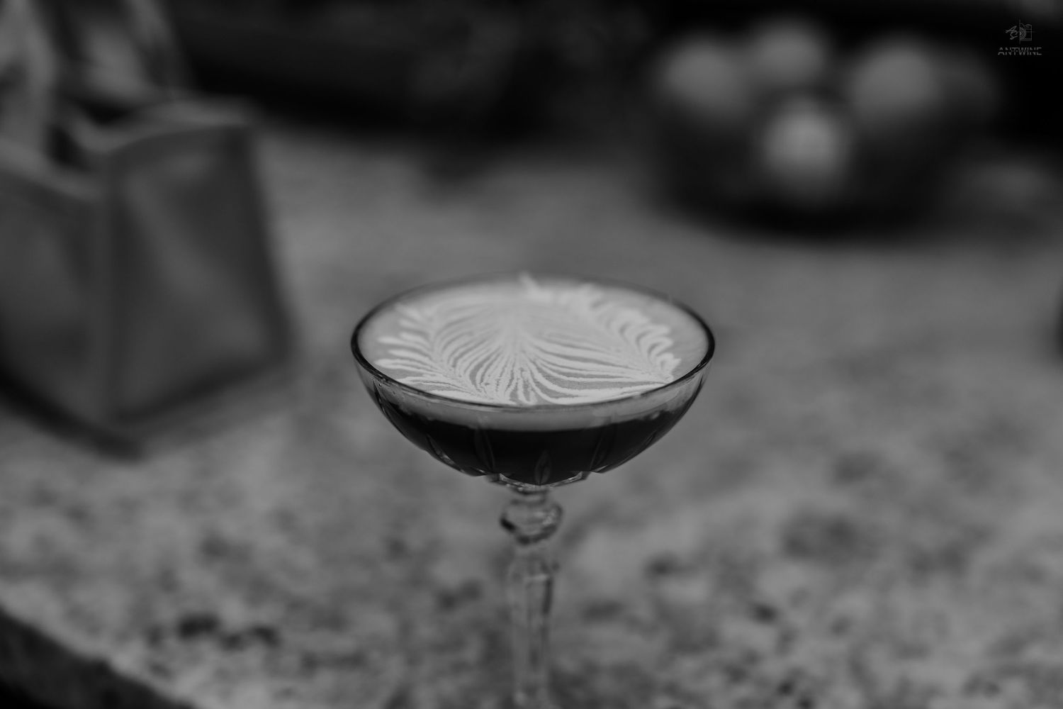 Elegant espresso martini cocktail in coupe glass with decorative foam art in black and white.