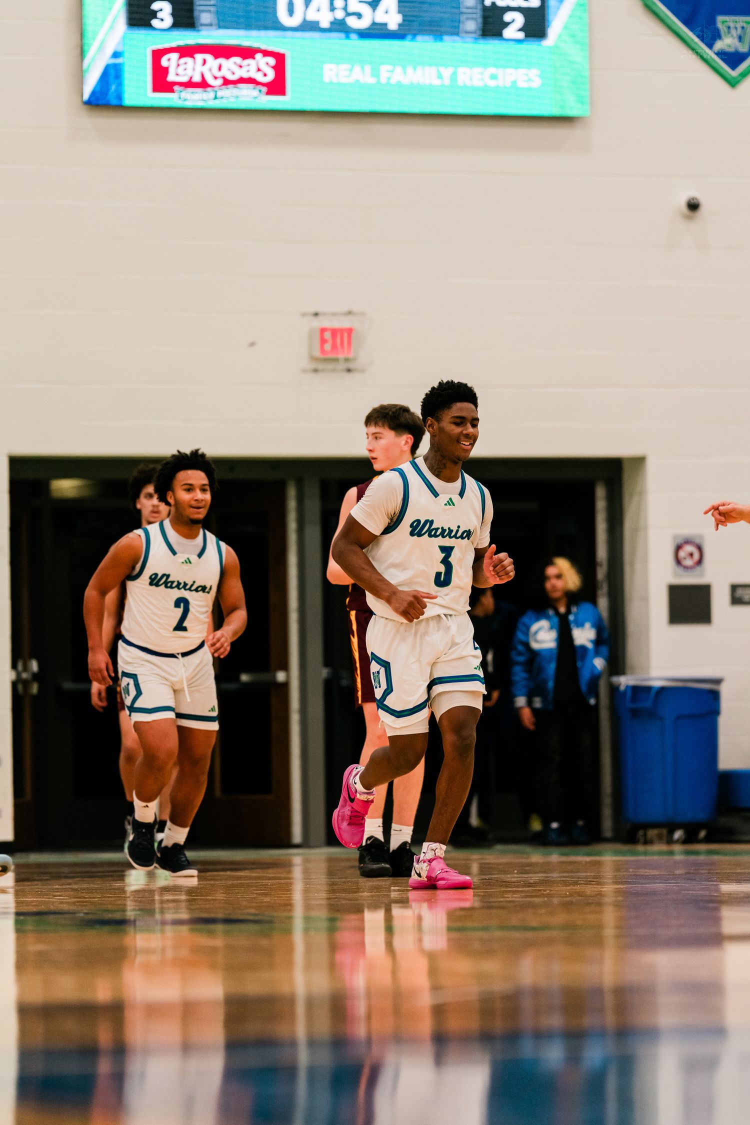 Warriors basketball players #3 and #2 run onto the court with scoreboard showing 3-2 at 4:54 game time.
