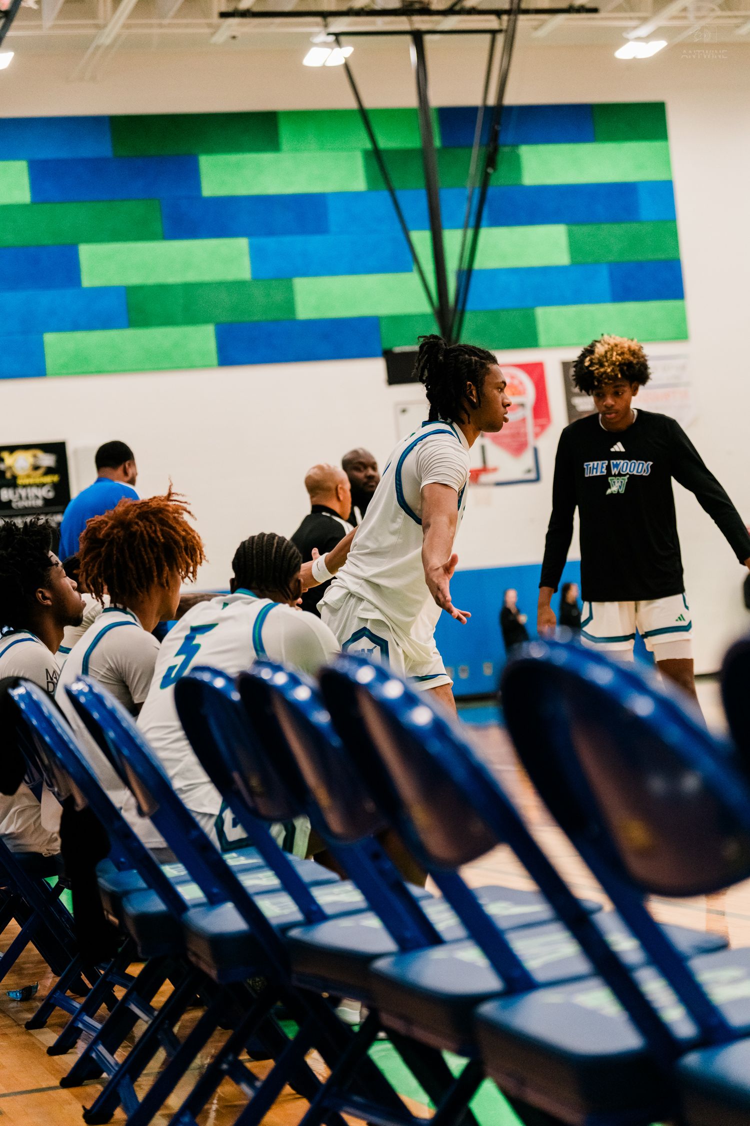 Basketball players in white uniforms gather near bench during game.