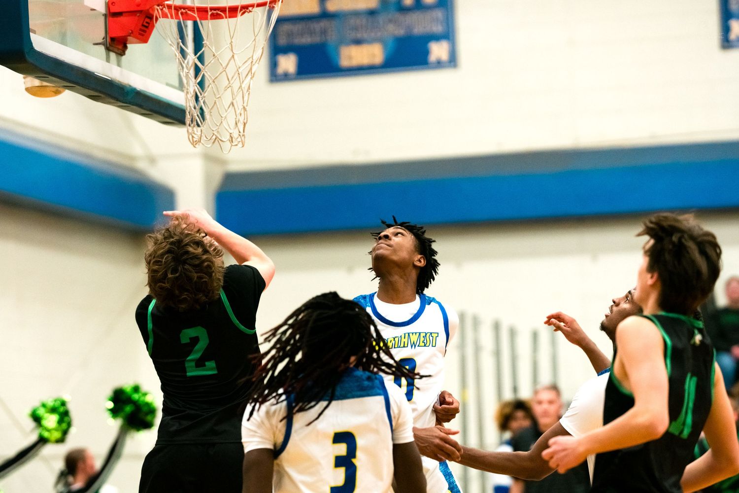 Players battle for rebound under basket during high school basketball game.