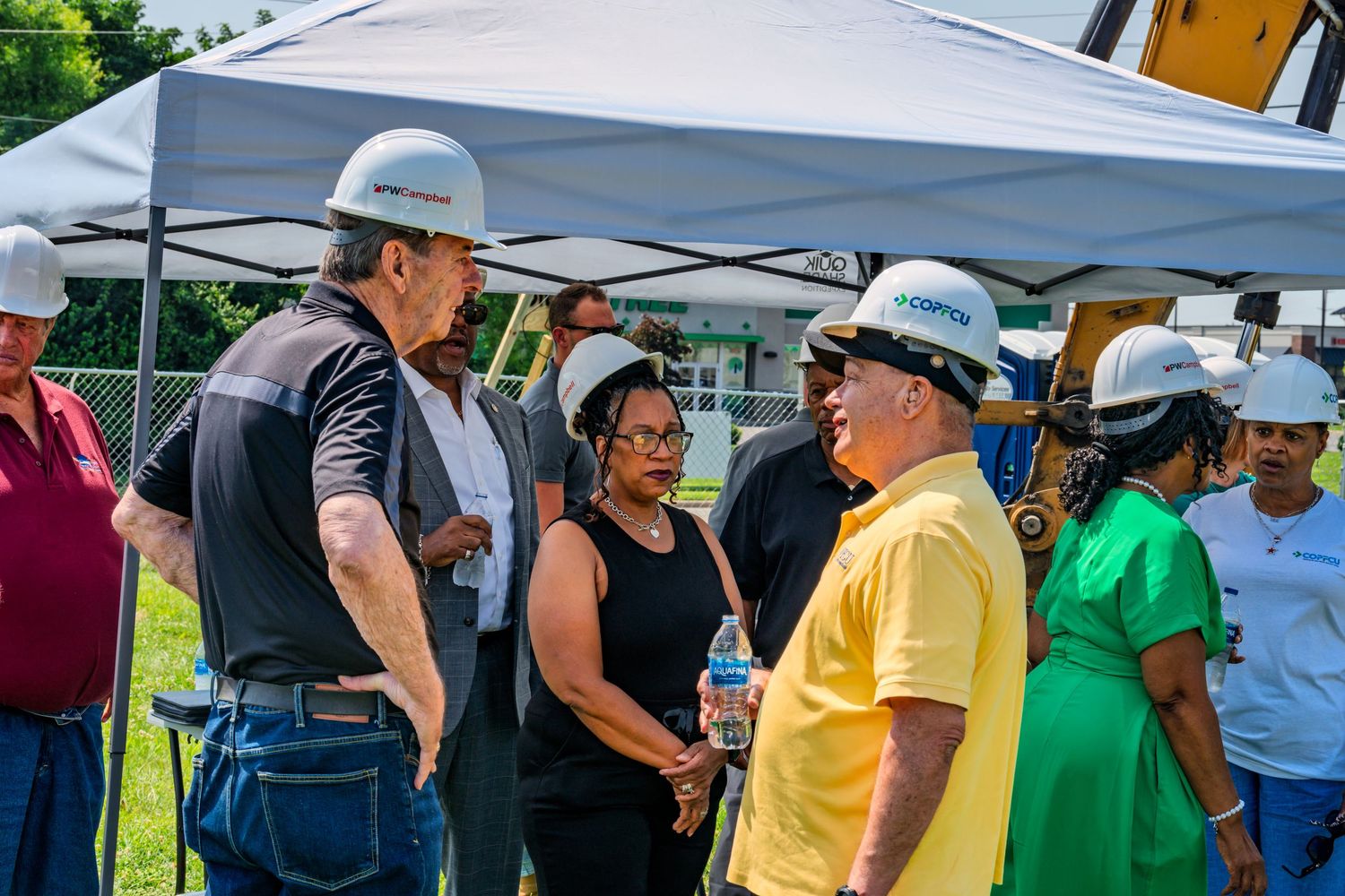 Group of people in hard hats having a discussion at a COPFCU groundbreaking event.