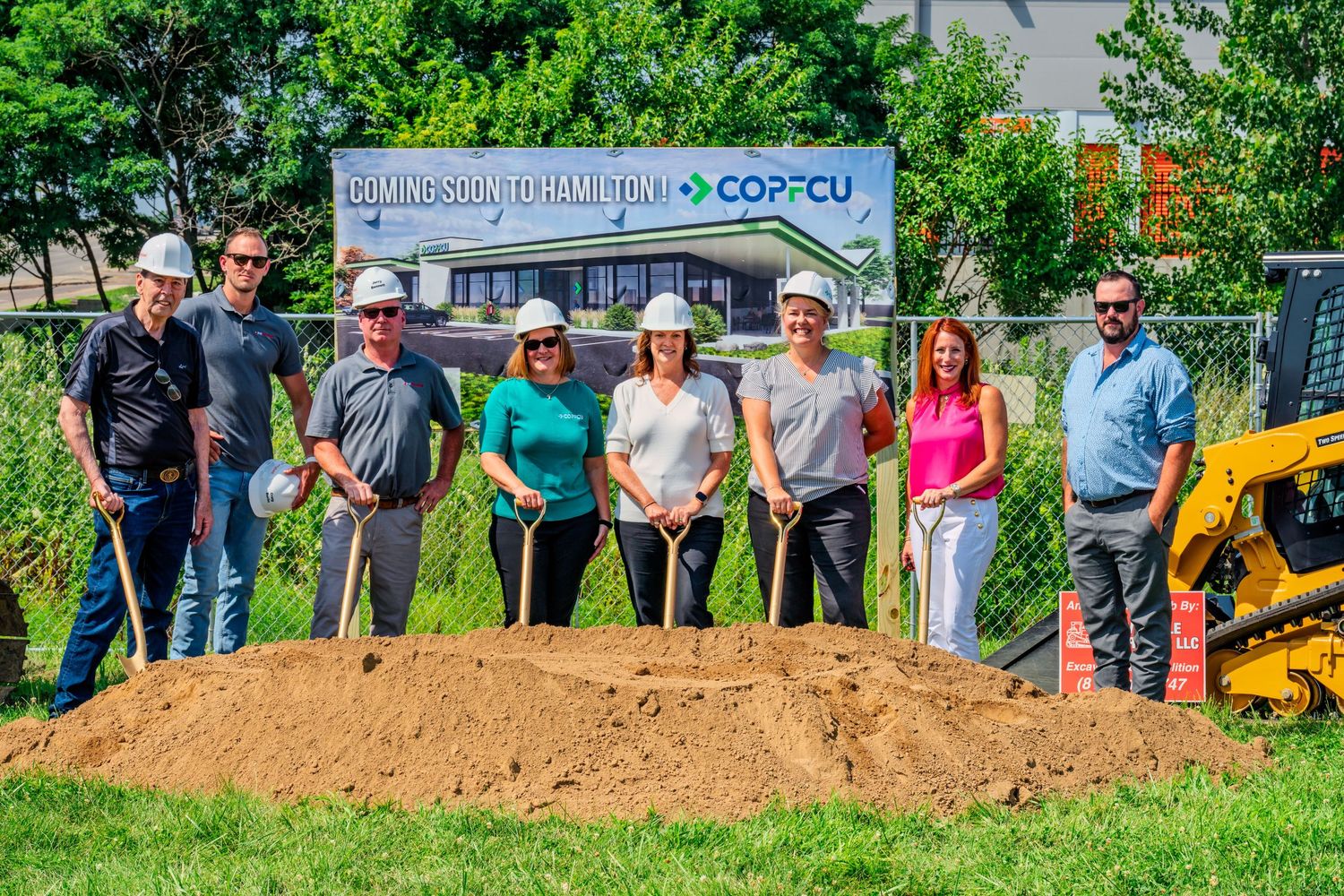 Eight people in hard hats with shovels celebrate COPFCU Hamilton new branch groundbreaking ceremony.