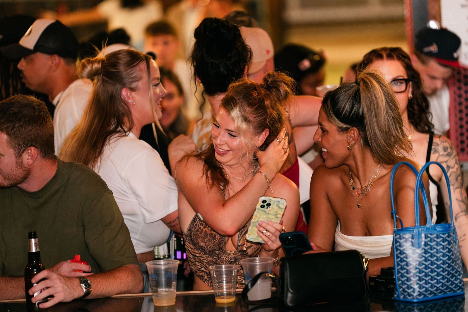 Friends laughing and enjoying drinks together at a busy bar.