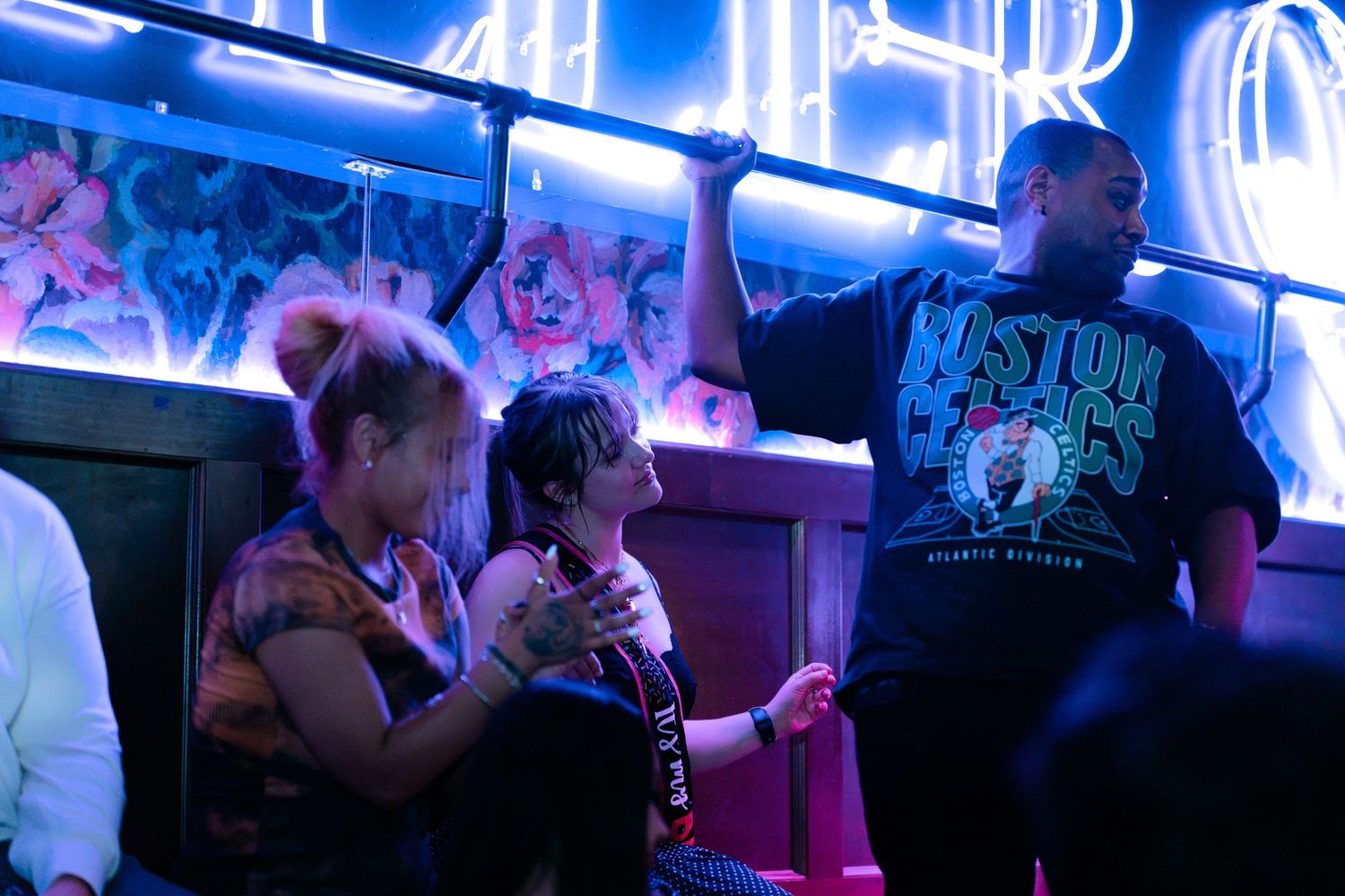 People dancing at a vibrant nightclub with neon lights and music.