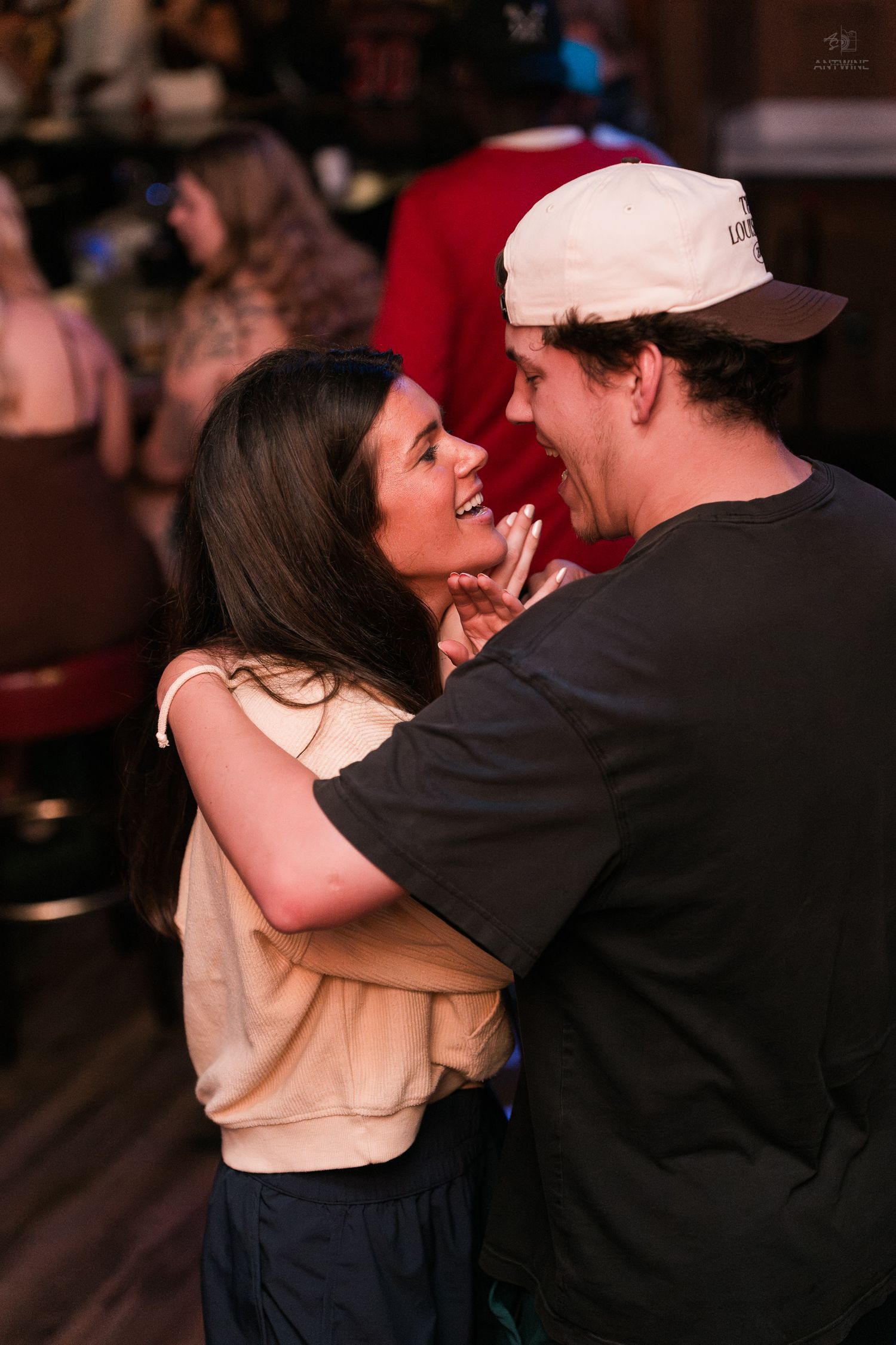 Young couple smiling and embracing while dancing together inside a warmly lit bar venue.
