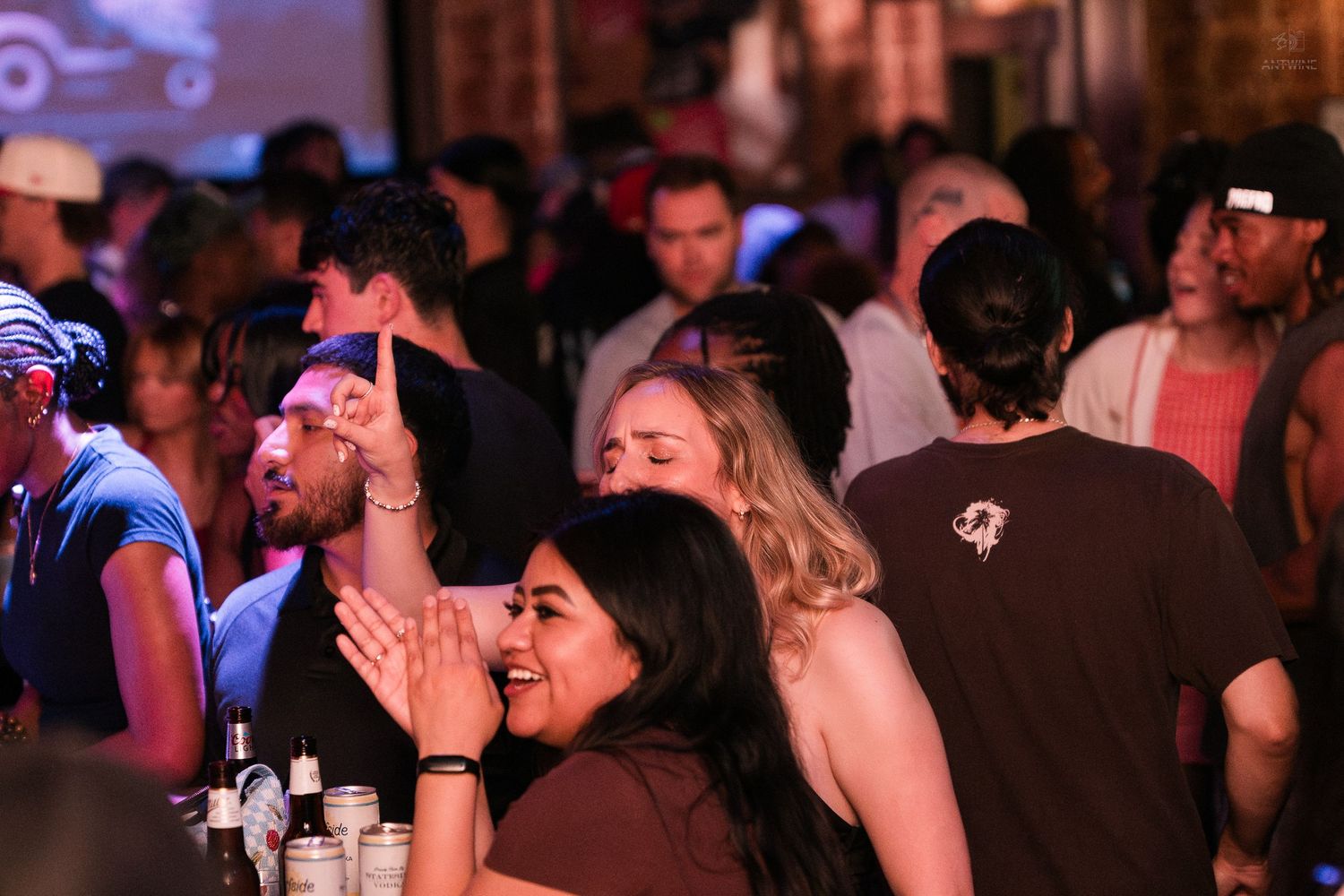 Group of people laughing and socializing at a busy nightclub or bar event.