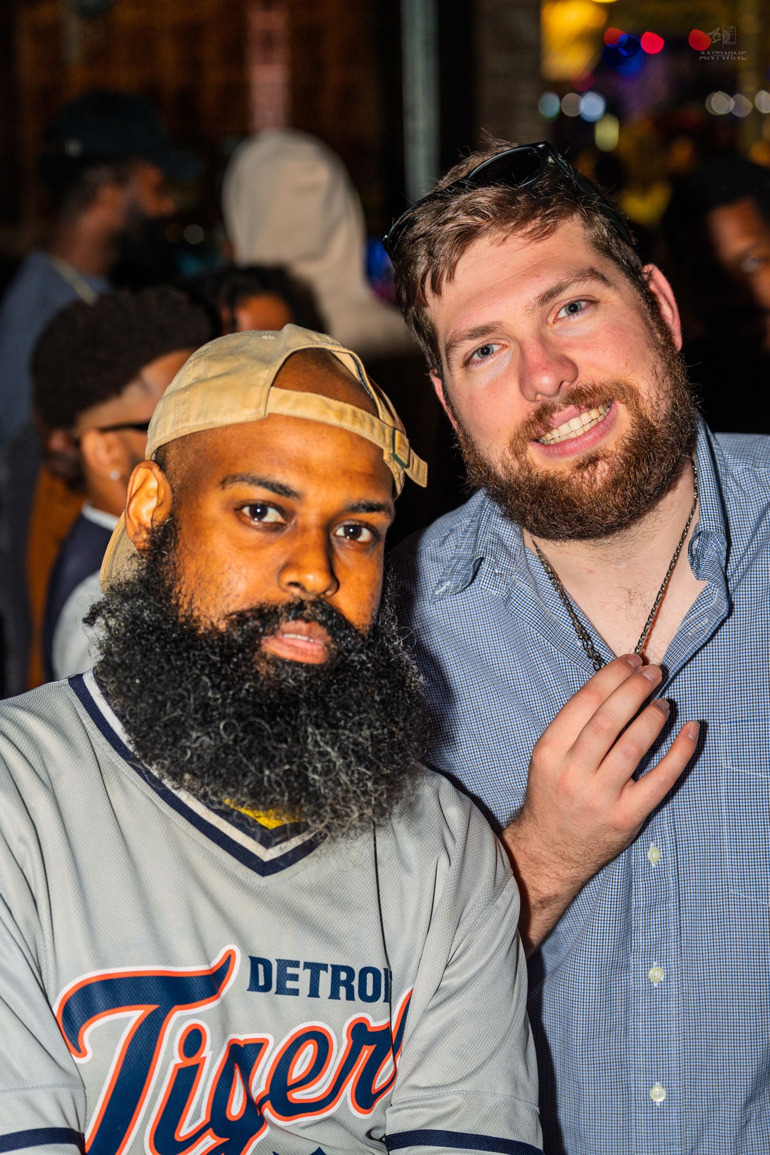 Two smiling men pose together outdoors, one wearing a Detroit Tigers jersey.