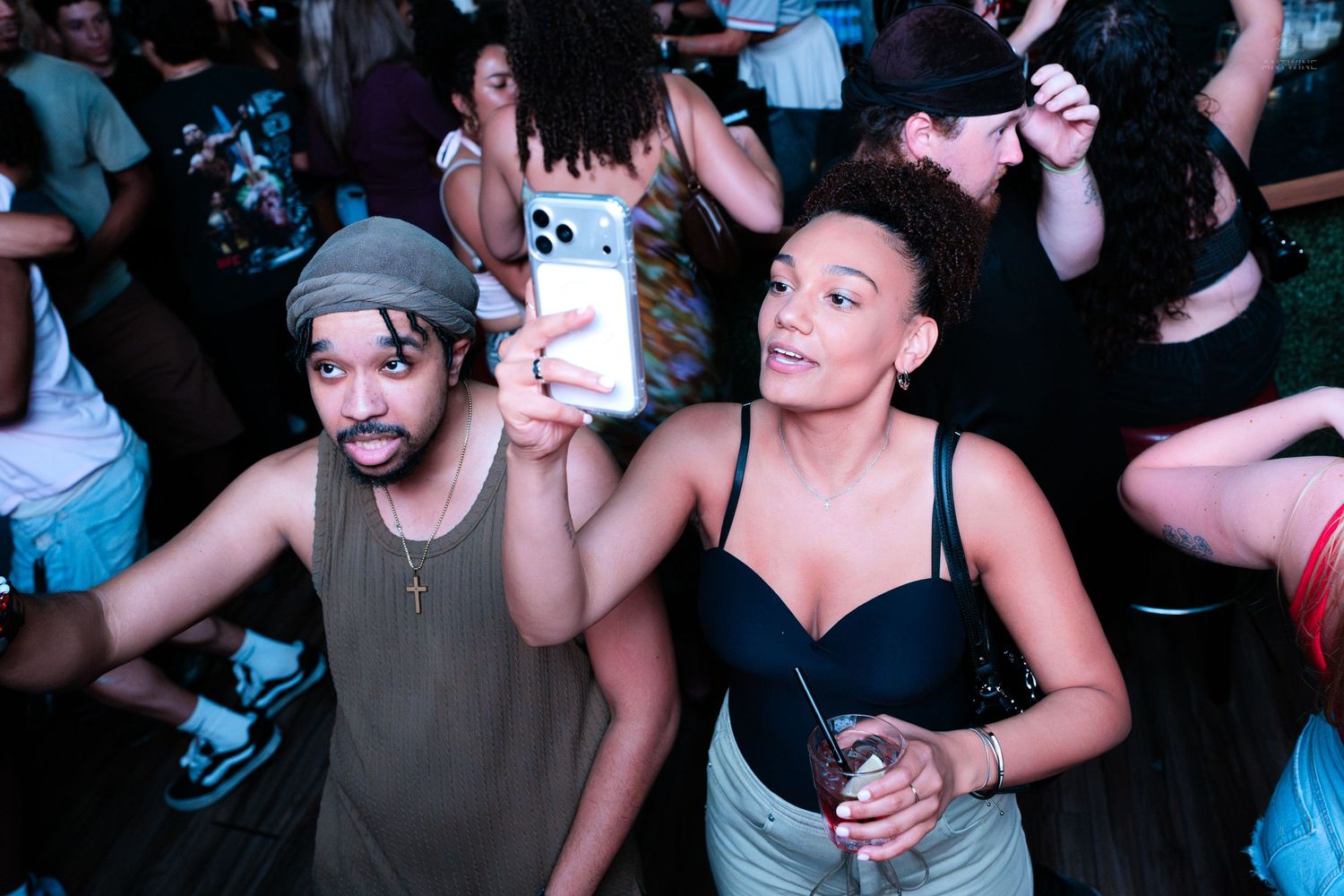 Couple taking a selfie while enjoying drinks at a lively nightclub event.