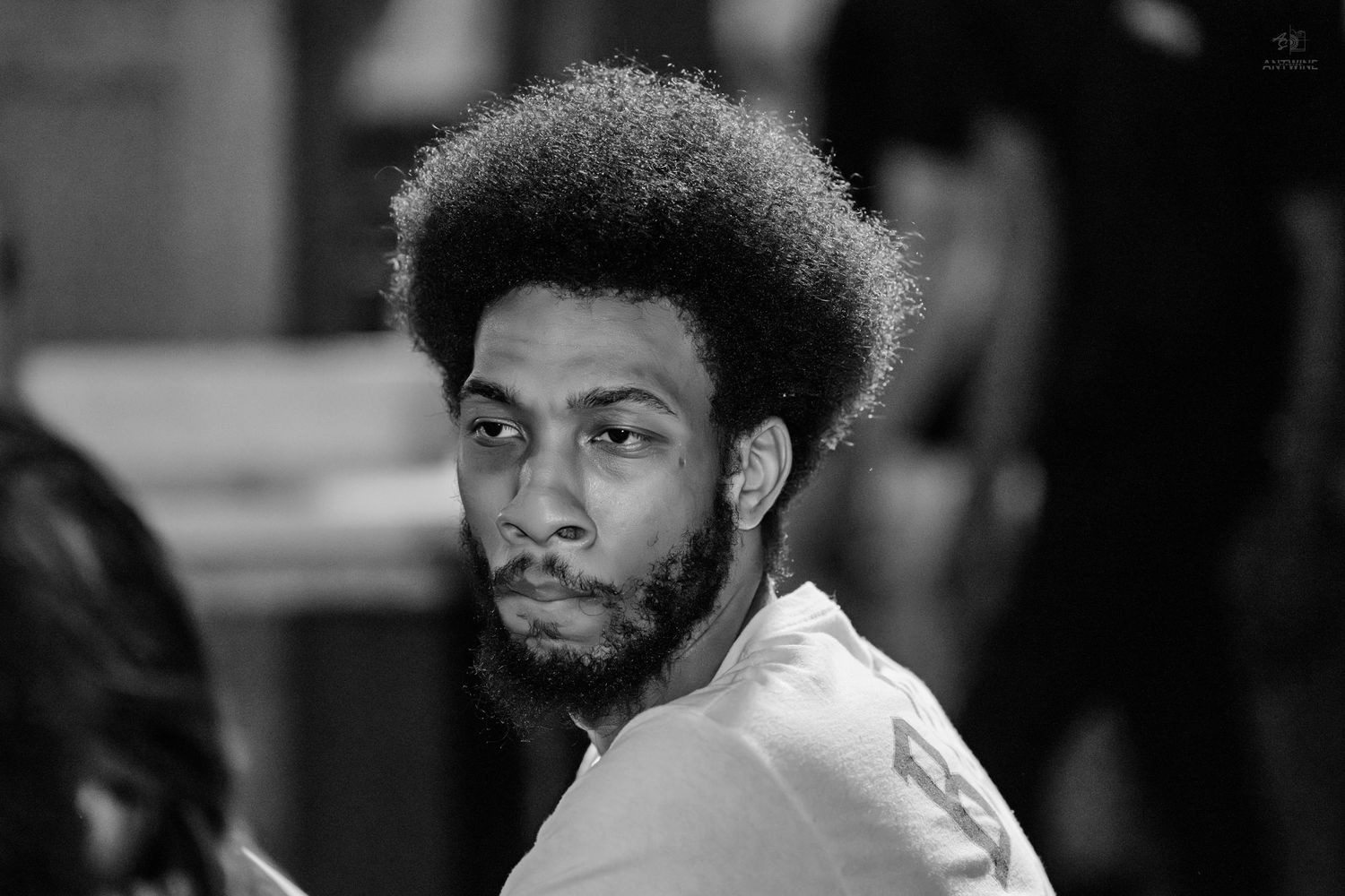 Black and white portrait of a man with an afro at a social event.
