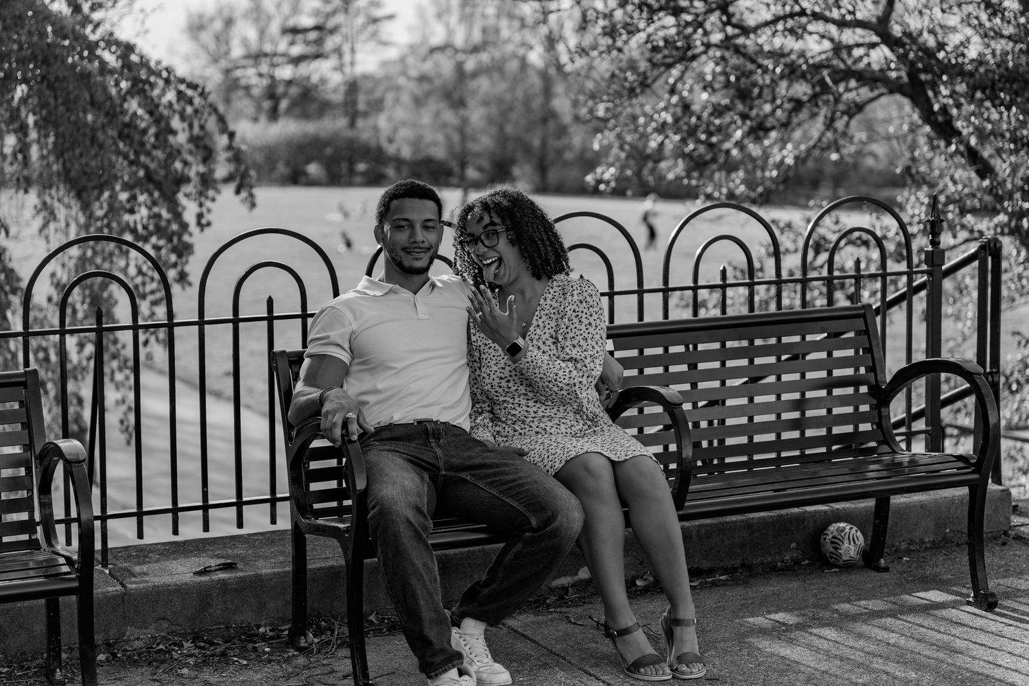 Black and white photo of a laughing couple sitting closely together on a park bench.