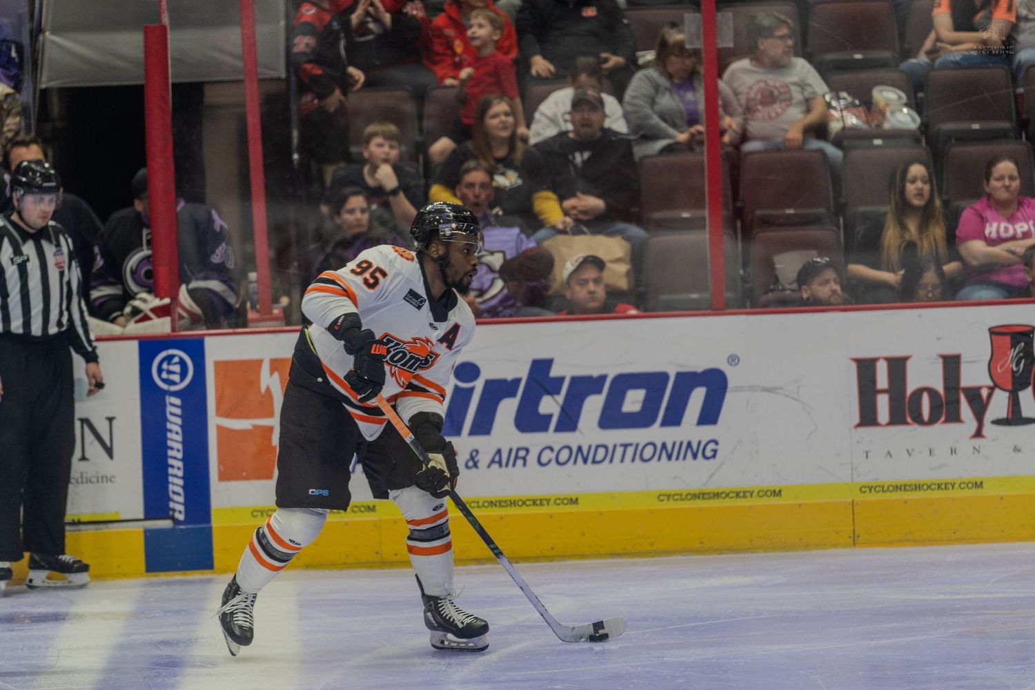 Hockey player controls the puck along the boards during a professional ice hockey game.