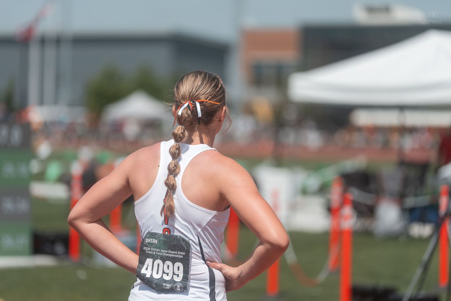 Female track athlete with bib number 4099 stands with hands on hips at a track and field competition.