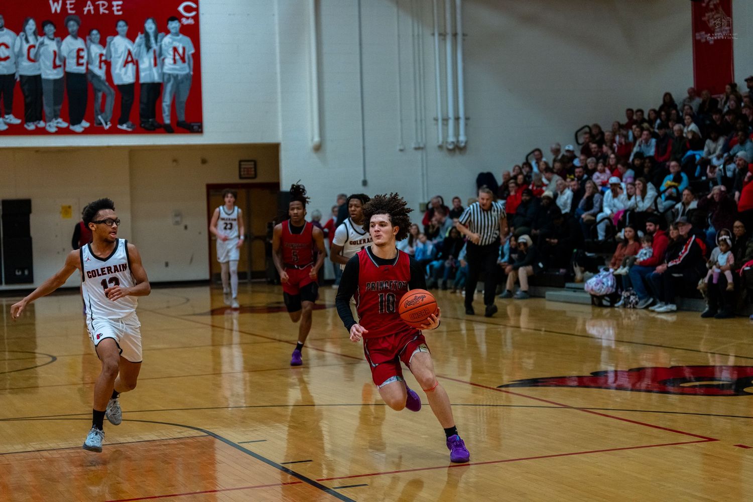 Basketball player in red dribbles toward the basket during a high school basketball game.