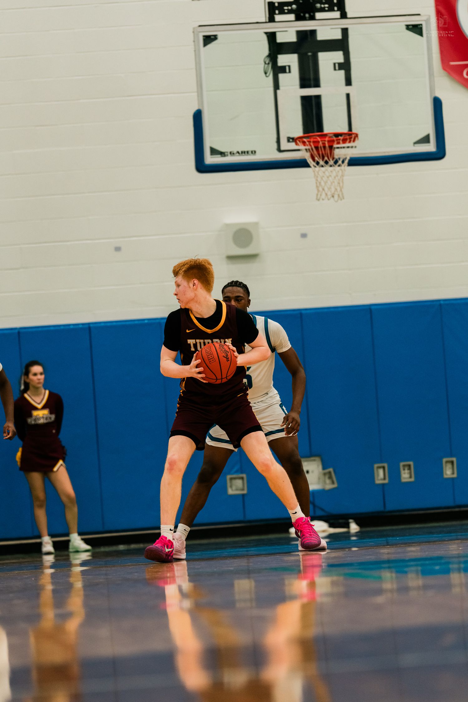 Turpin high school basketball player holds the ball while being defended near the basket during a game.