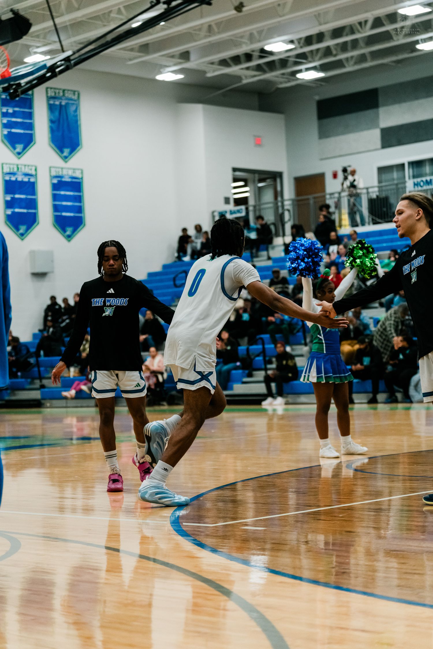 Basketball player number 0 runs onto court greeted by cheerleaders.