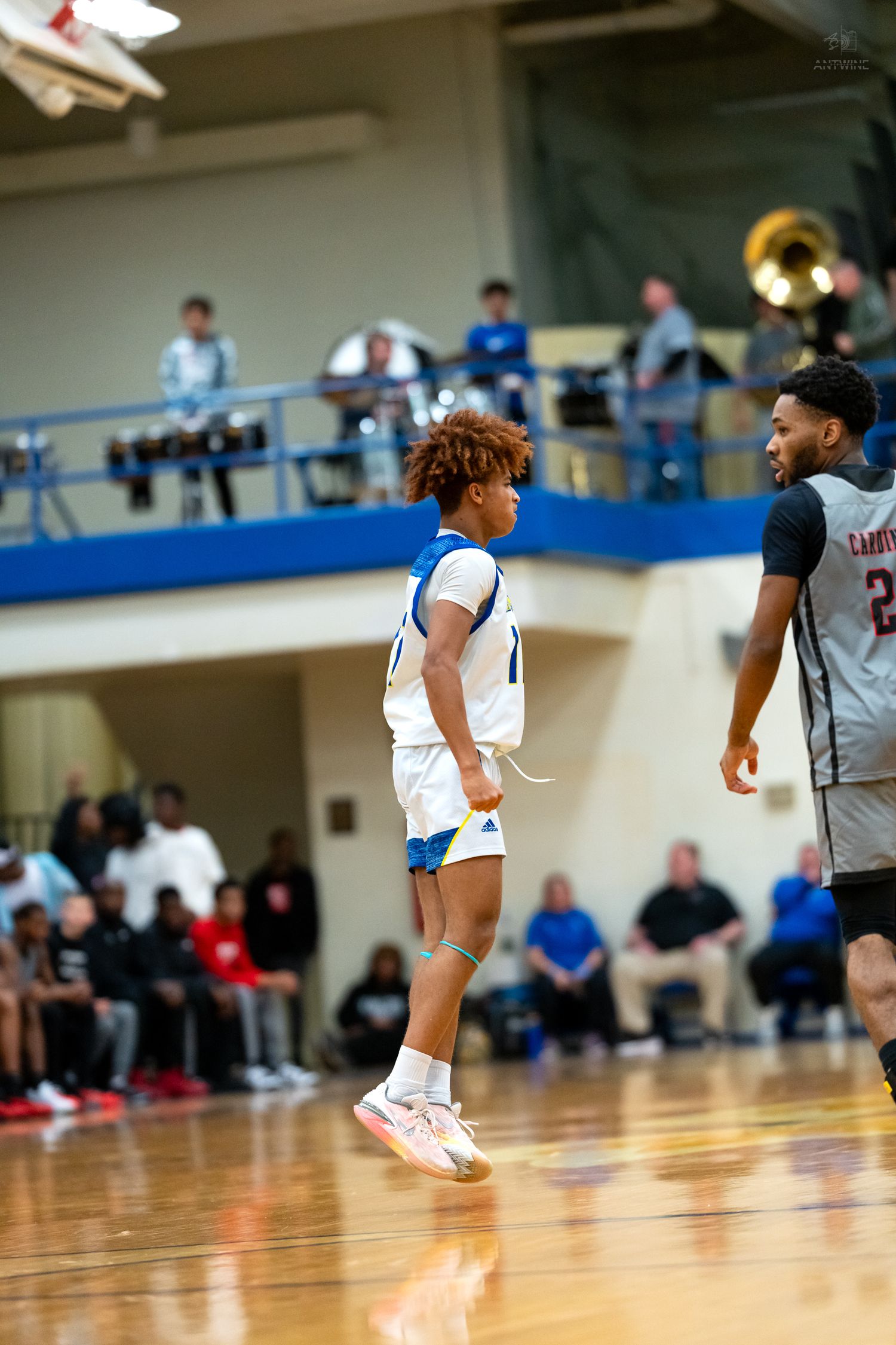 Basketball player #11 in blue white uniform faces opponent #22 on hardwood court during school game.