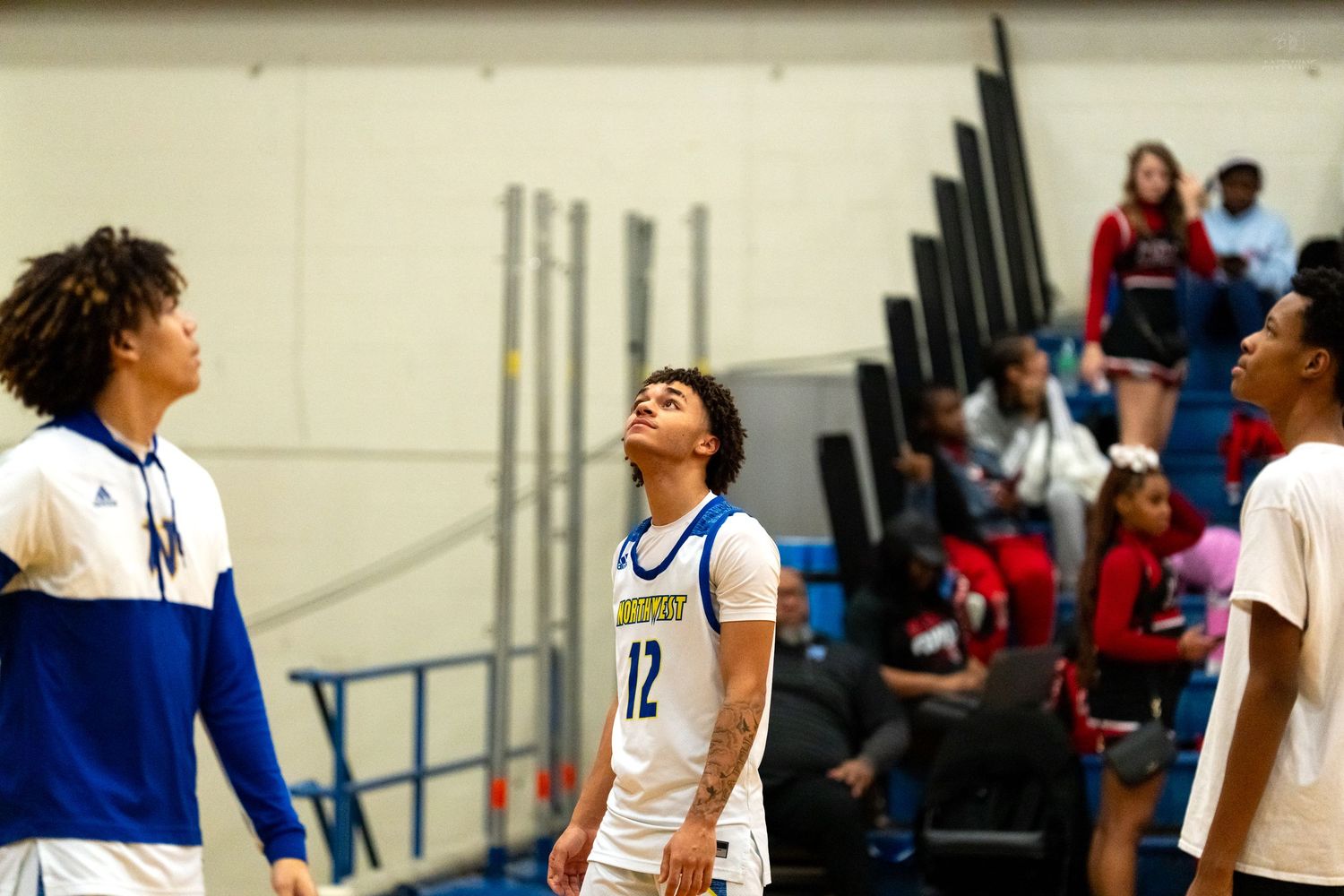 Player #12 looks up at the scoreboard with teammates during a high school basketball game timeout.