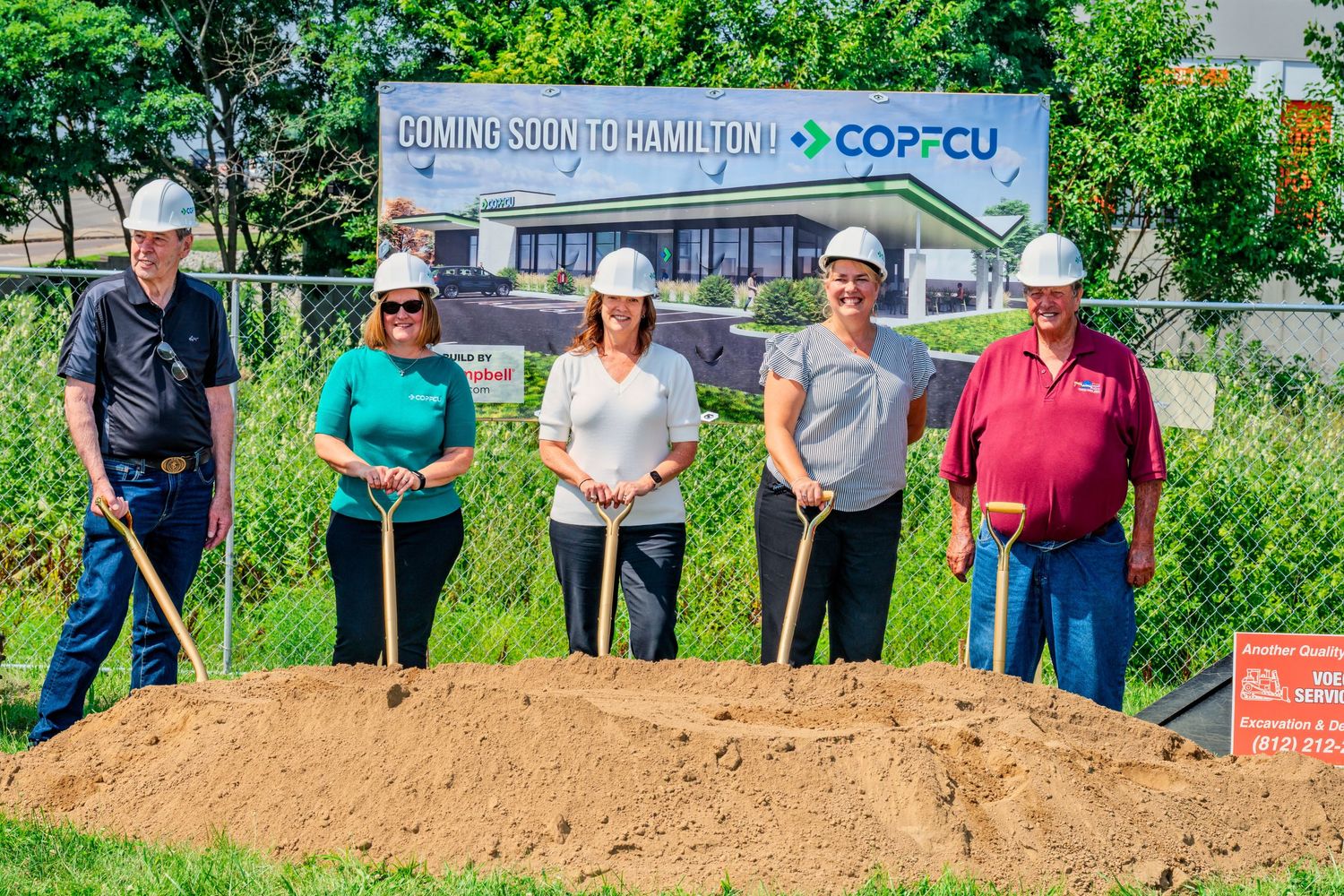 Five people in hard hats holding shovels pose at COPFCU Hamilton groundbreaking ceremony outdoors.