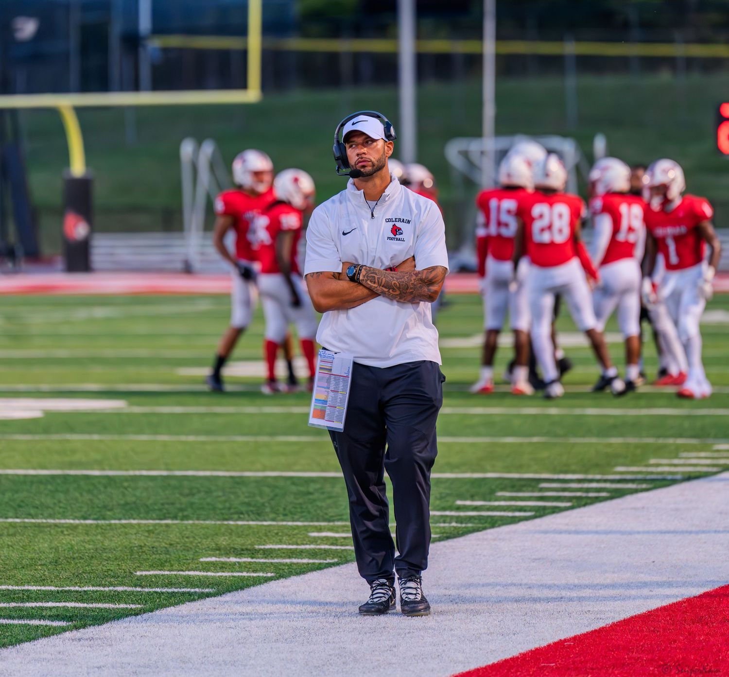 Colerain Cardinals head coach observes practice on the sideline during a high school football game.