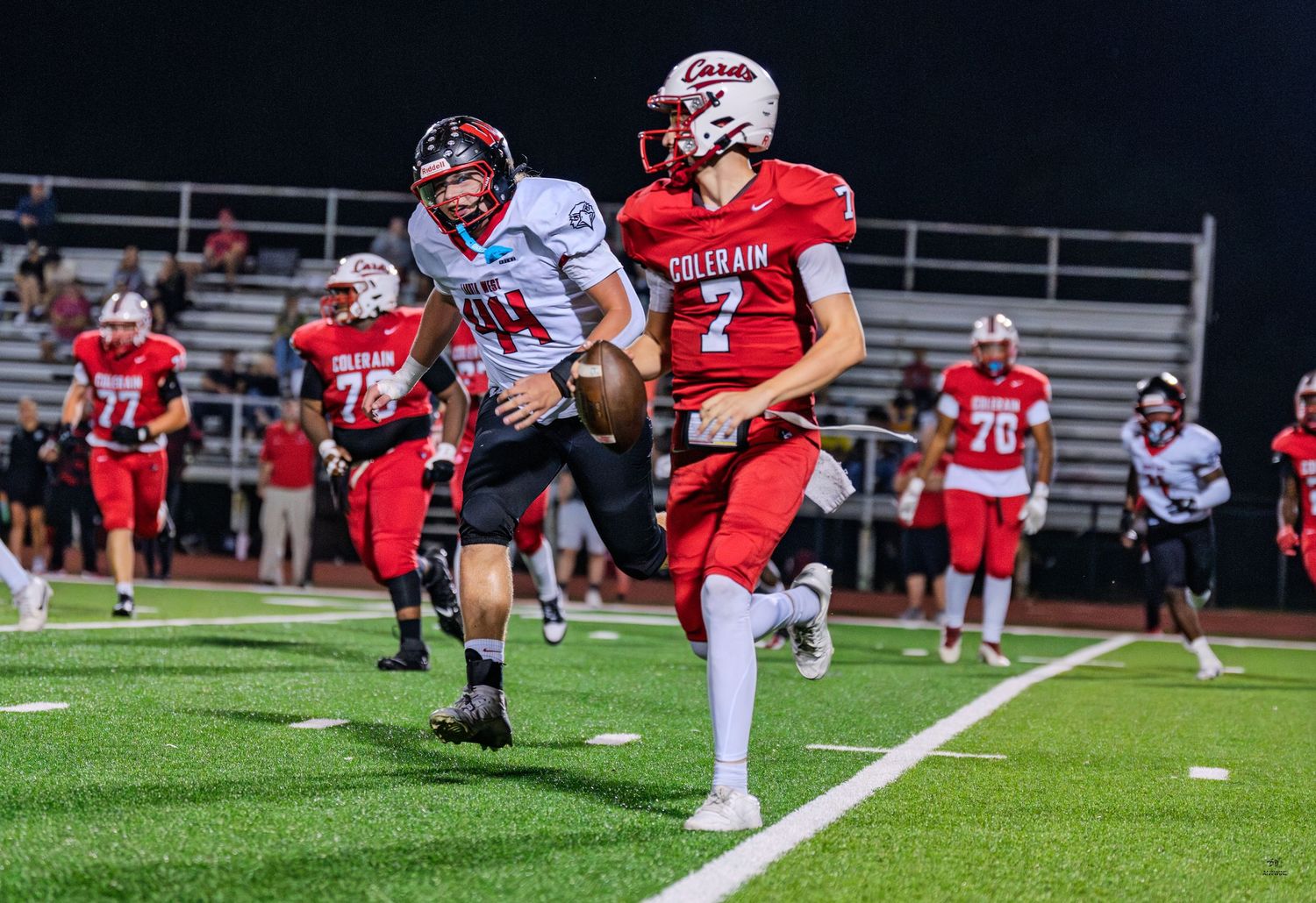 Colerain Cardinals quarterback #7 scrambles along the sideline during a night game.
