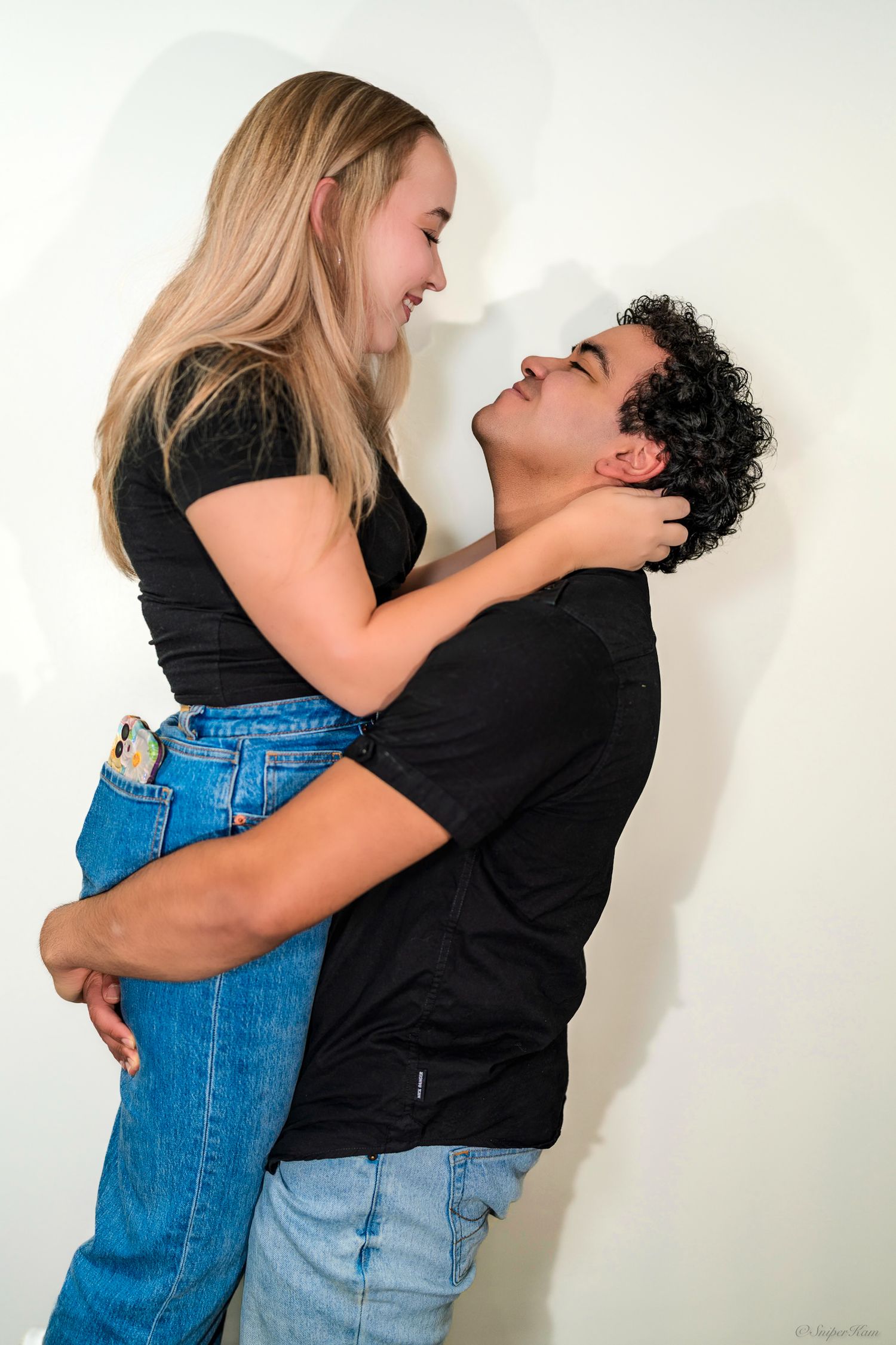 Couple smiling and embracing closely, woman holding mans face gently in color photo.