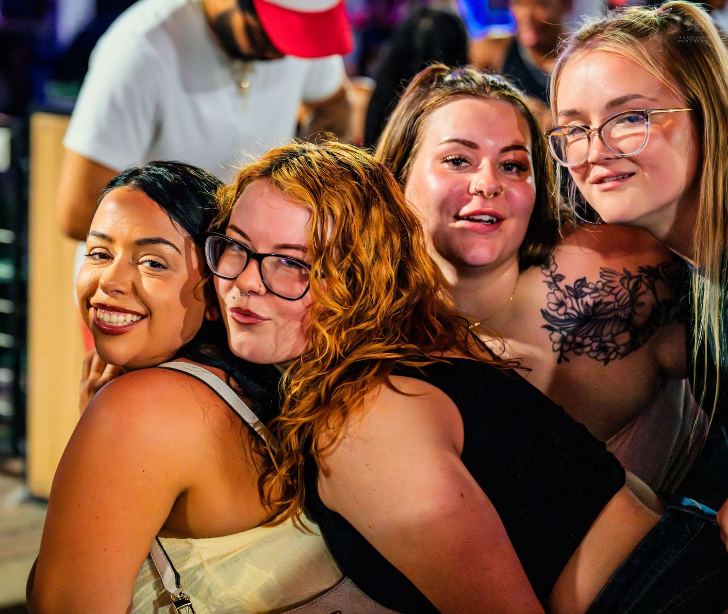 Four smiling women pose together for a fun group photo at a nightclub.