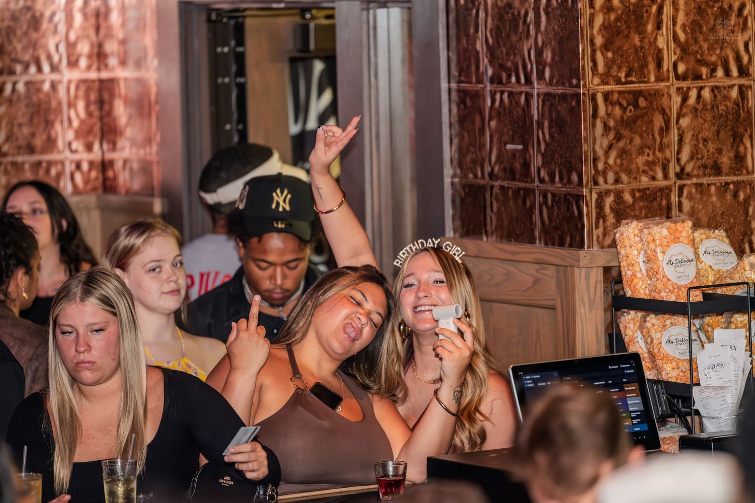 Excited group of friends celebrating at a bar, with one man making a rock gesture.