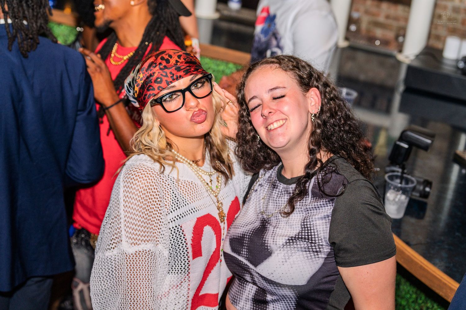 Two women posing together making faces at a party event.