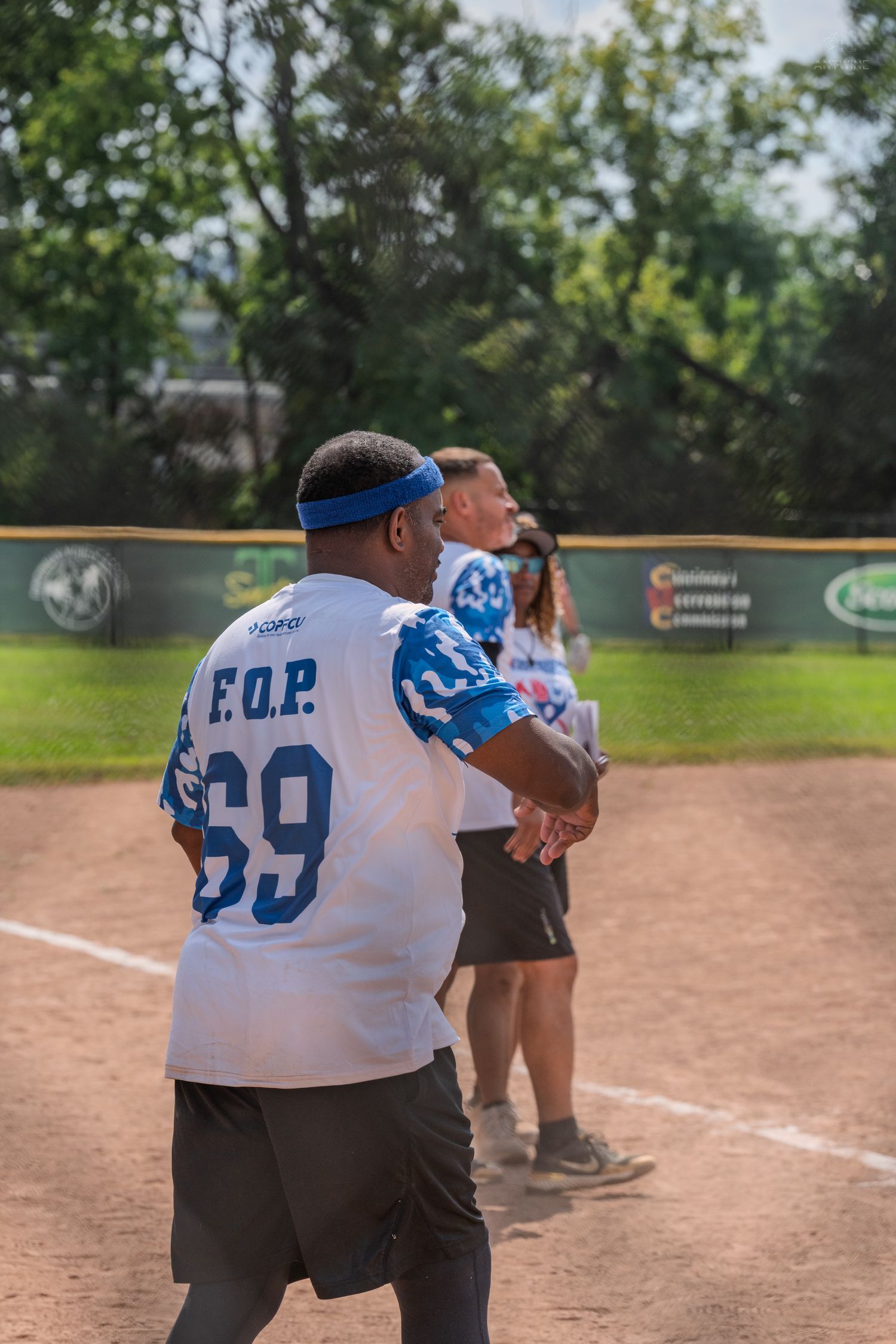 softball player wearing FOP number 69 jersey stands on the baseline during an outdoor charity softball game.